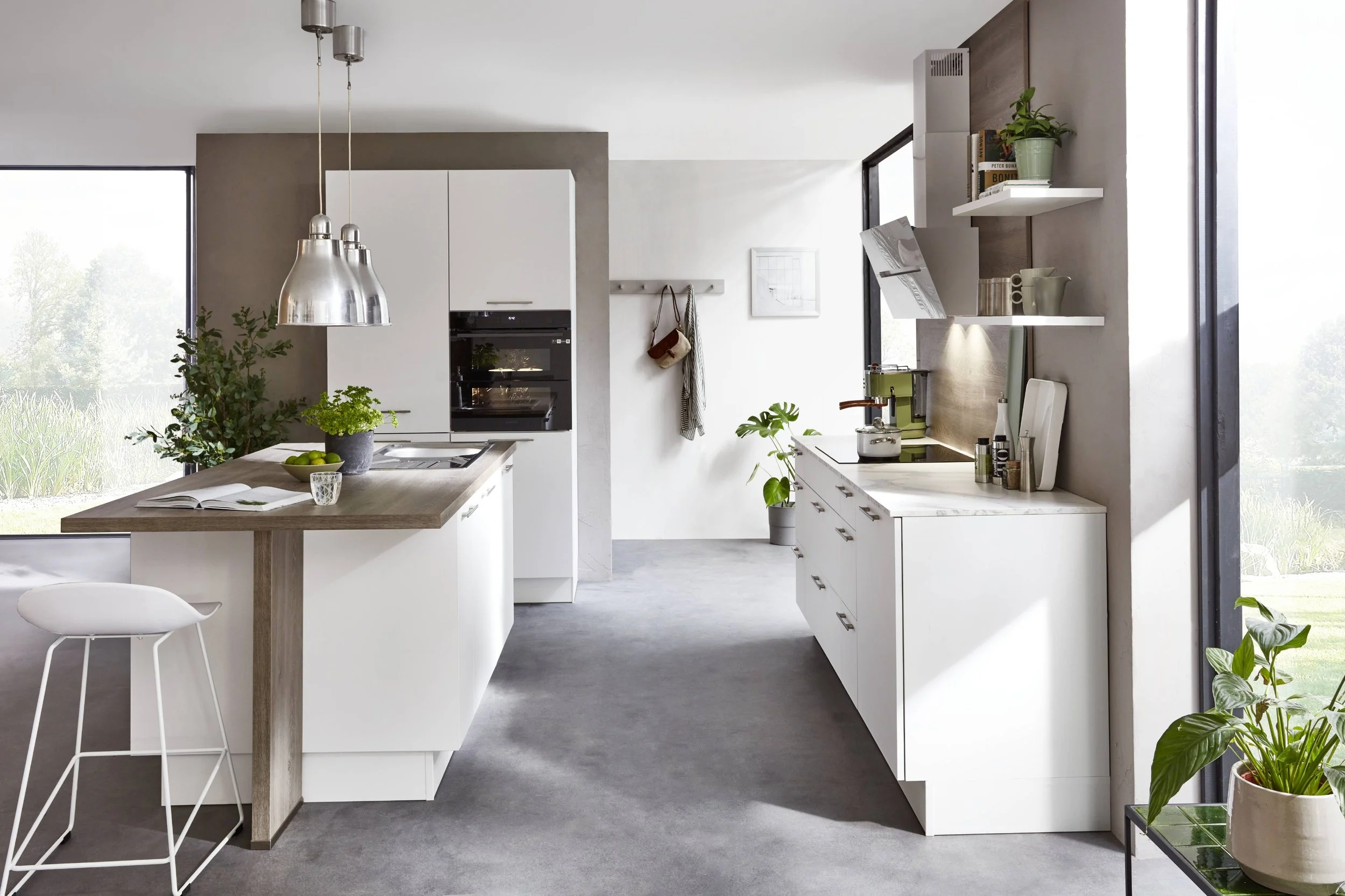 Modern kök med vita skåp, köksö, ställ med växter, stora fönster, svart stänkskydd, öppna hyllor och jordnära färger.