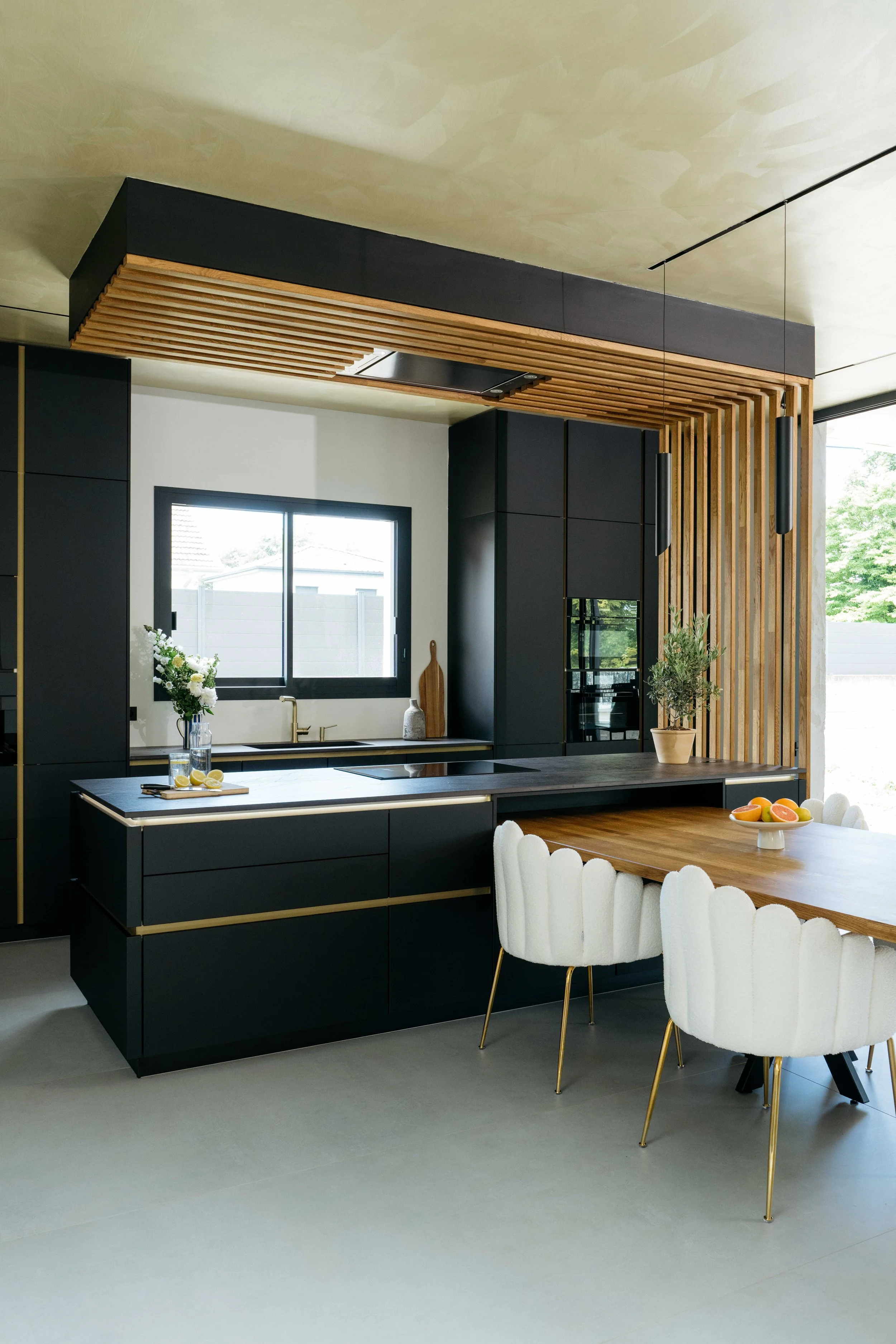 Modernt kök med svarta skåp, trädetaljer och en köksö.