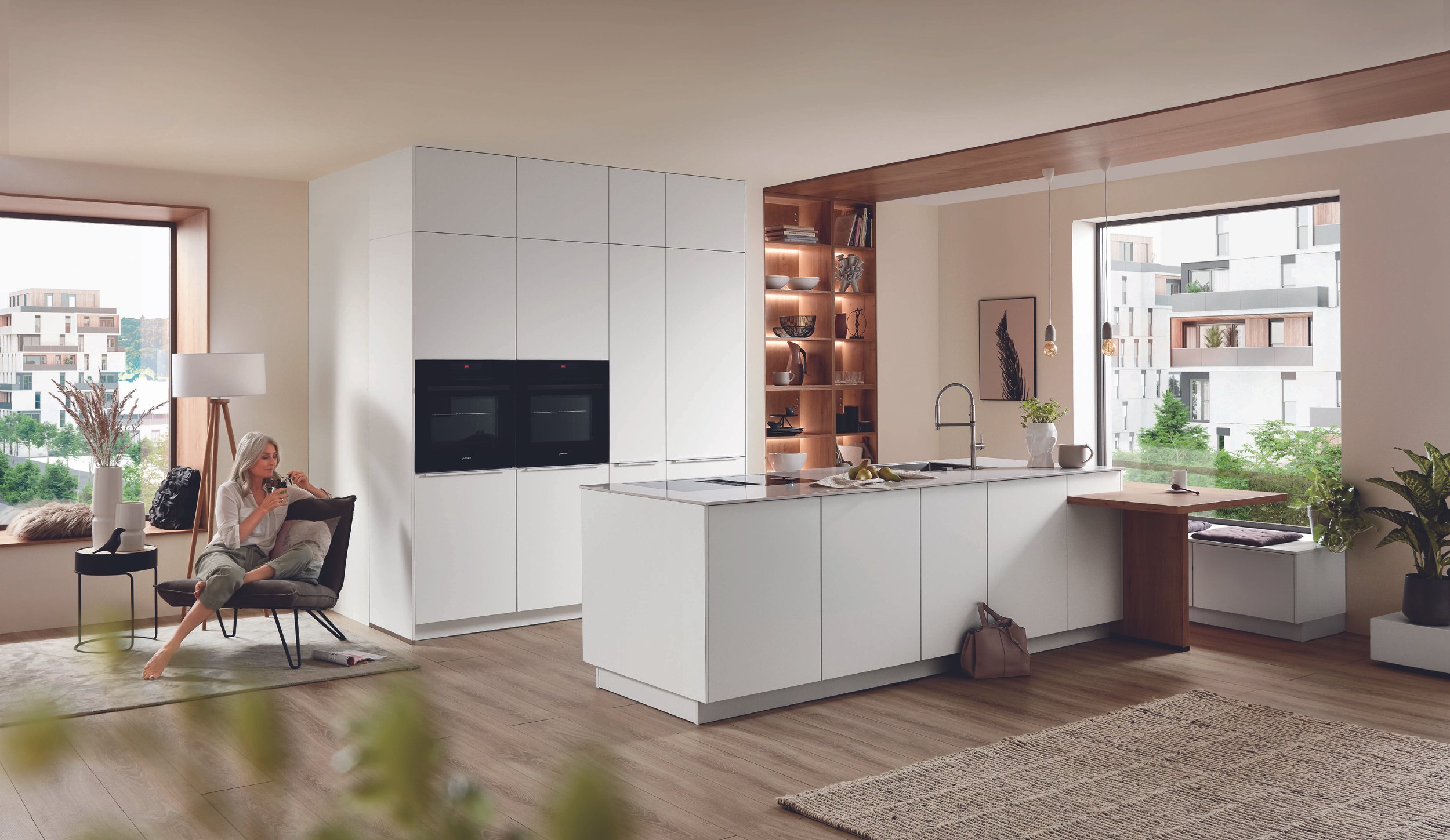 Moderne kök med vit skåp, köksö och stor fönster med utsikt över stadsdelar.