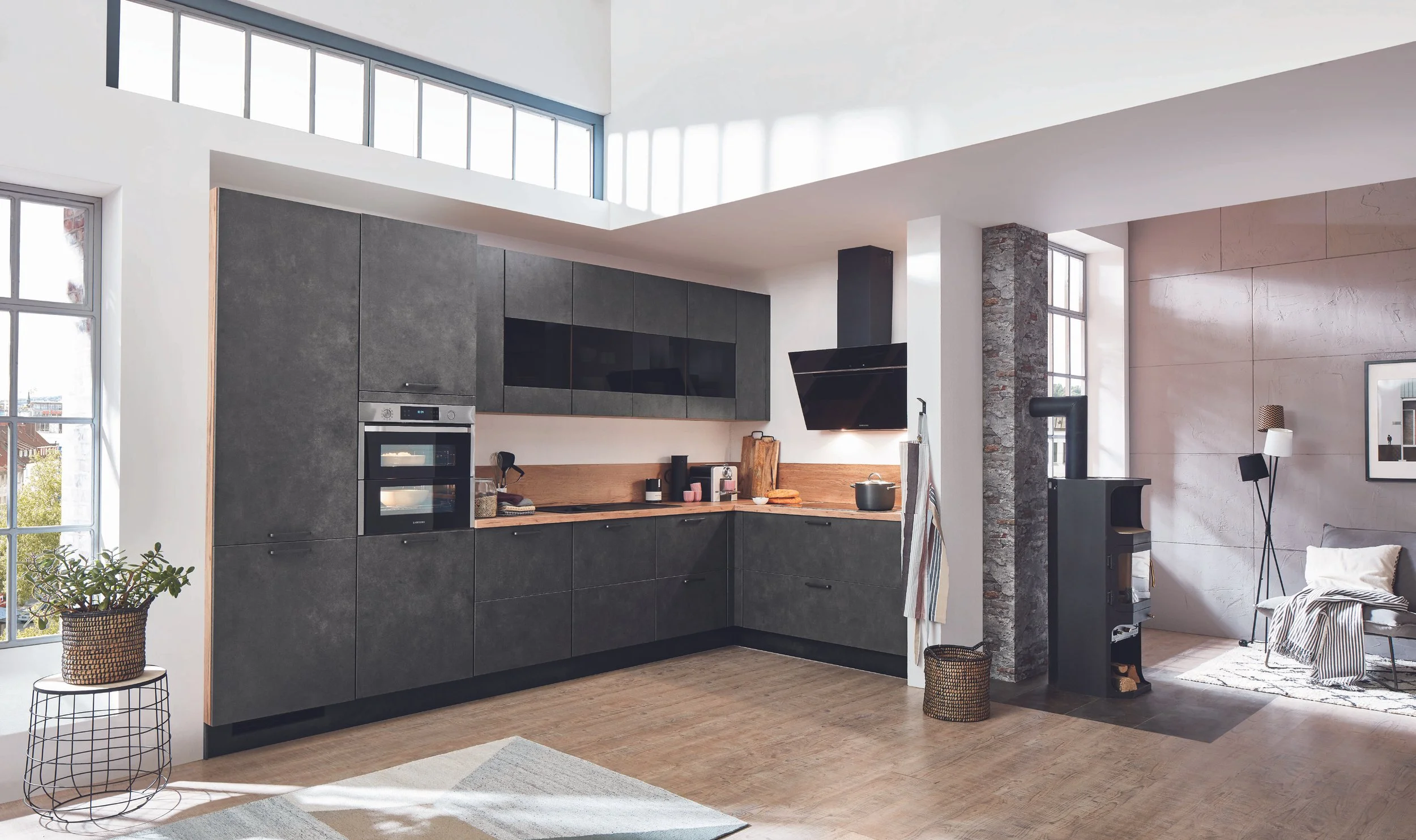 Moderna kök med svarta skåp, träbänkar och stor fönster. Vardagsrumsdel med soffa och golvlampa i bakgrunden.