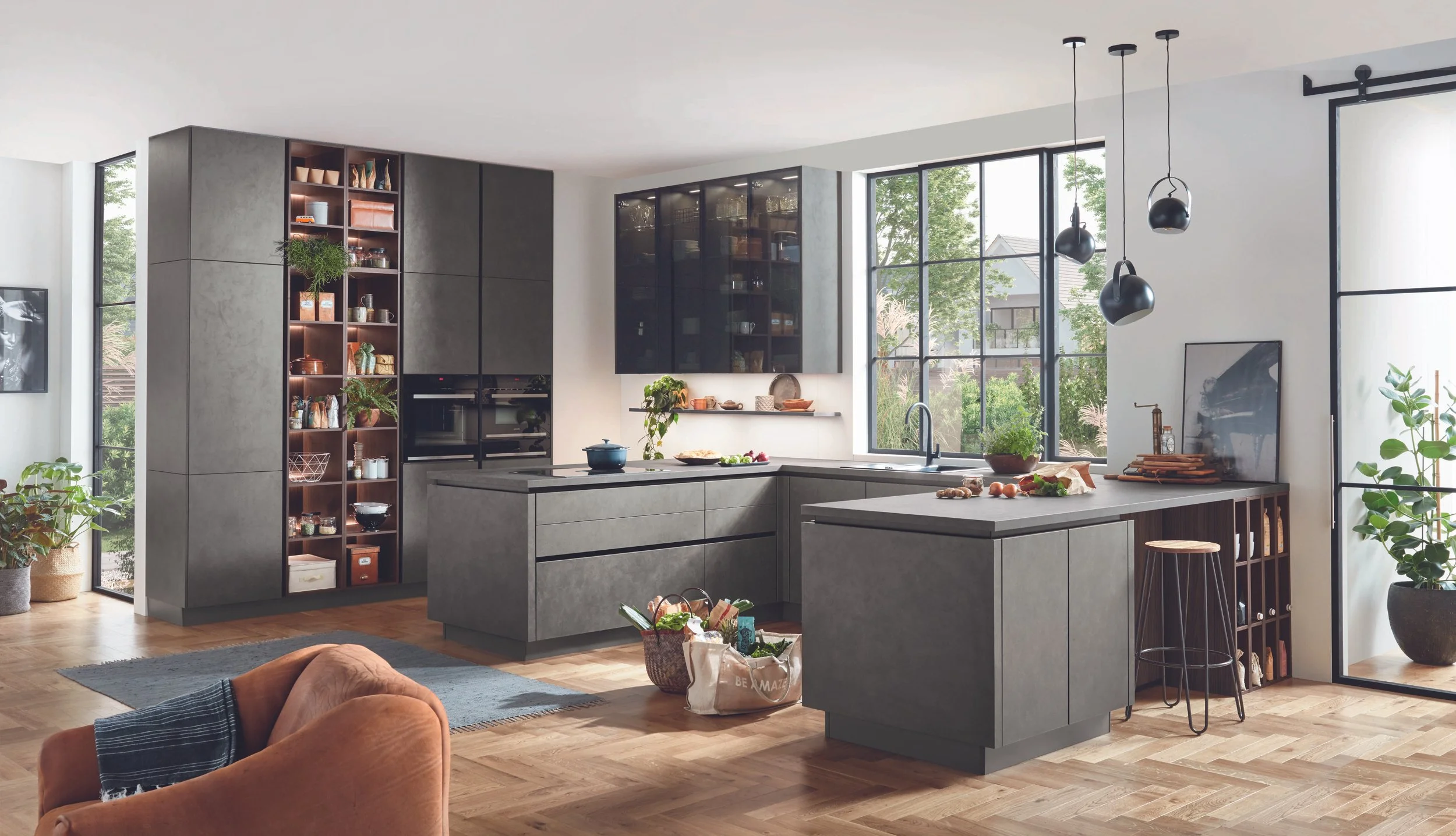 Modern köksinredning med grå skåp, köksö, stora fönster och trägolv