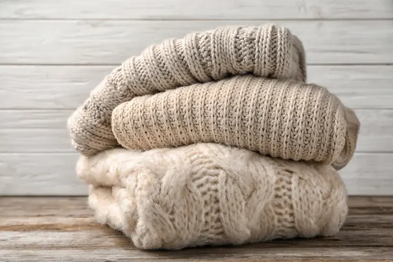 stack-folded-knitted-sweaters-table-130299642.webp