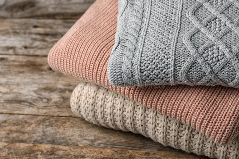 stack-folded-knitted-sweaters-table-closeup-131949930.webp