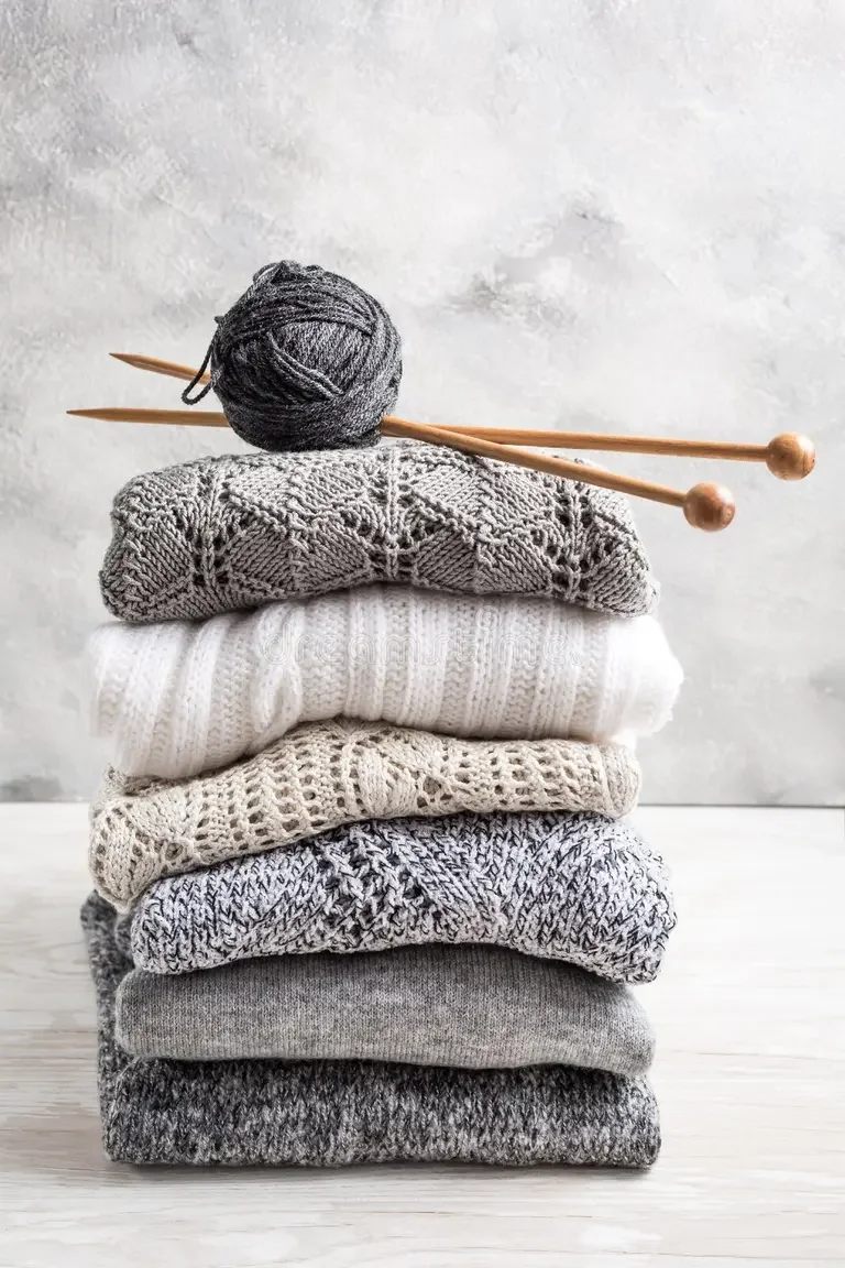stack-cozy-knitted-sweaters-pullovers-knitting-needles-wooden-background-stack-cozy-knitted-sweaters-218892105.webp