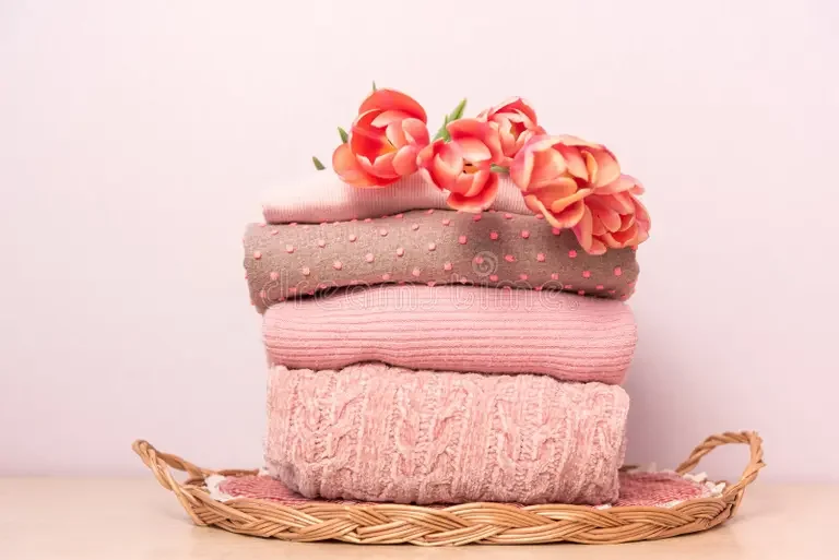 stack-womens-knitted-sweaters-wicker-tray-shelf-next-to-bouquet-flowers-folded-wool-pullovers-pink-pastel-colors-213002900.webp
