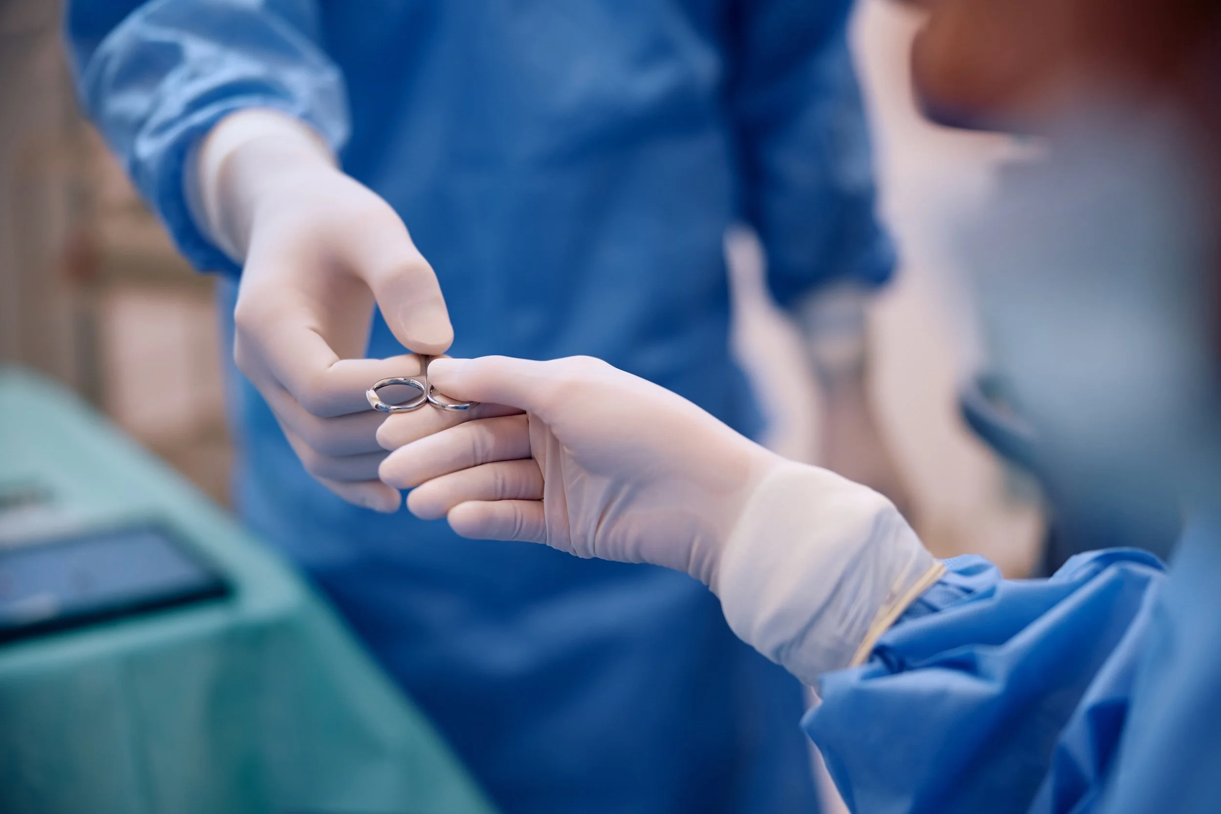Medical professionals in blue scrubs and white gloves exchanging wedding rings during a surgery or medical procedure.