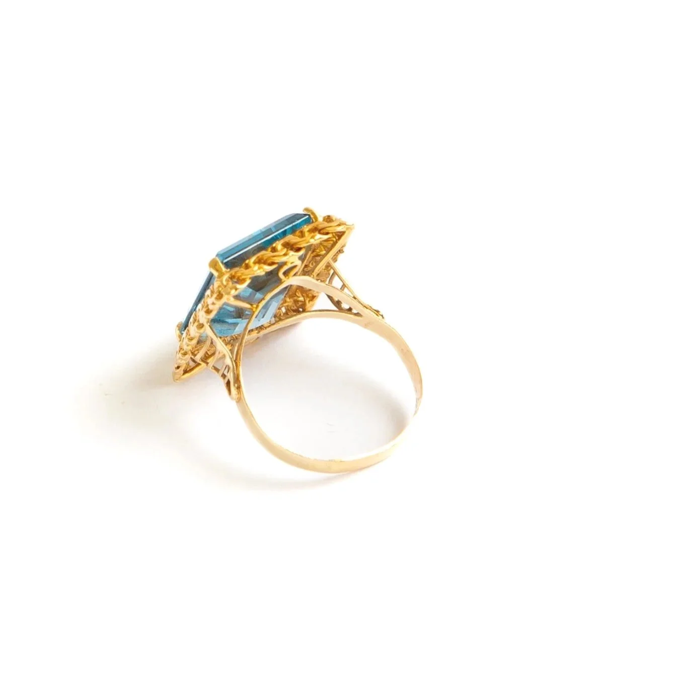 vintage 14k yellow gold ring featuring a large emerald cut blue topaz in a sculpted scrolled setting