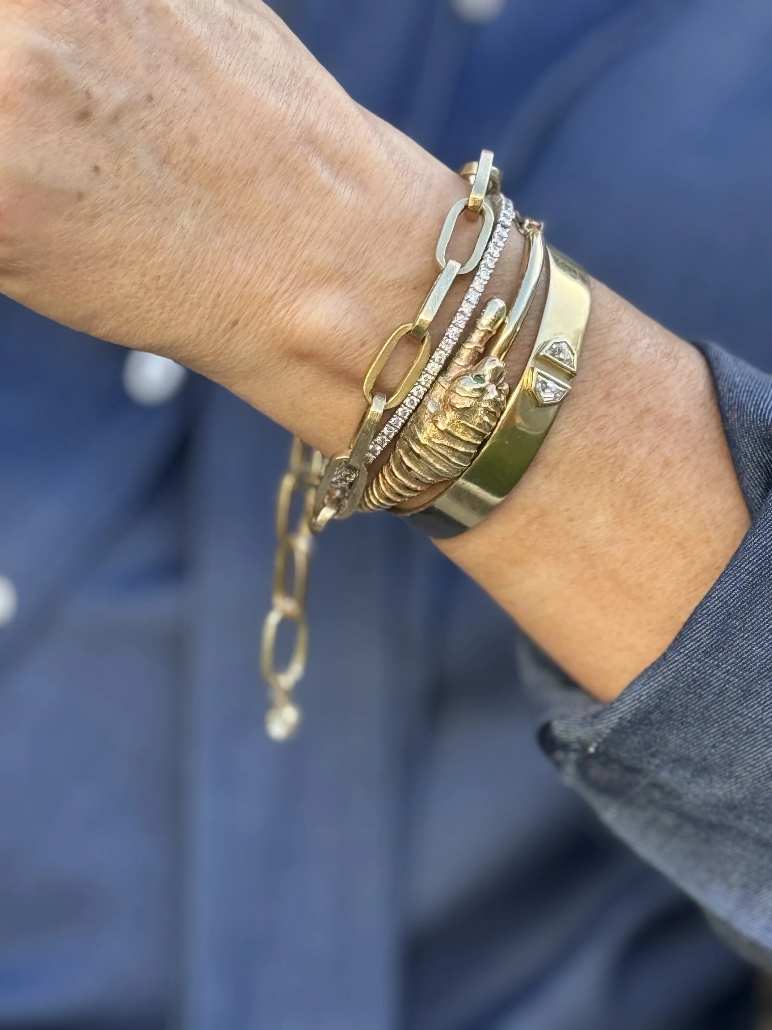 Vintage 9K yellow gold curb link bracelet layered with gold bangles and cuffs on wrist