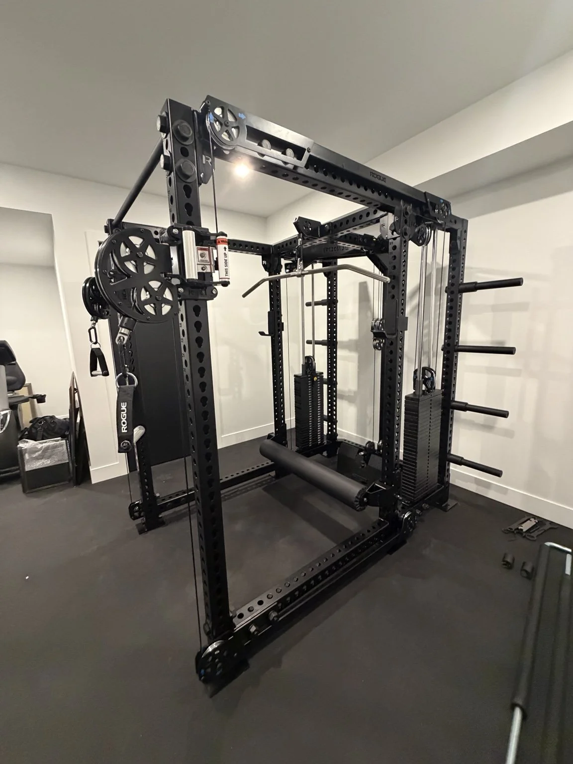 Rogue rack and cable machine on rubber flooring in a home gym, photographed during a 6IX Assembly project