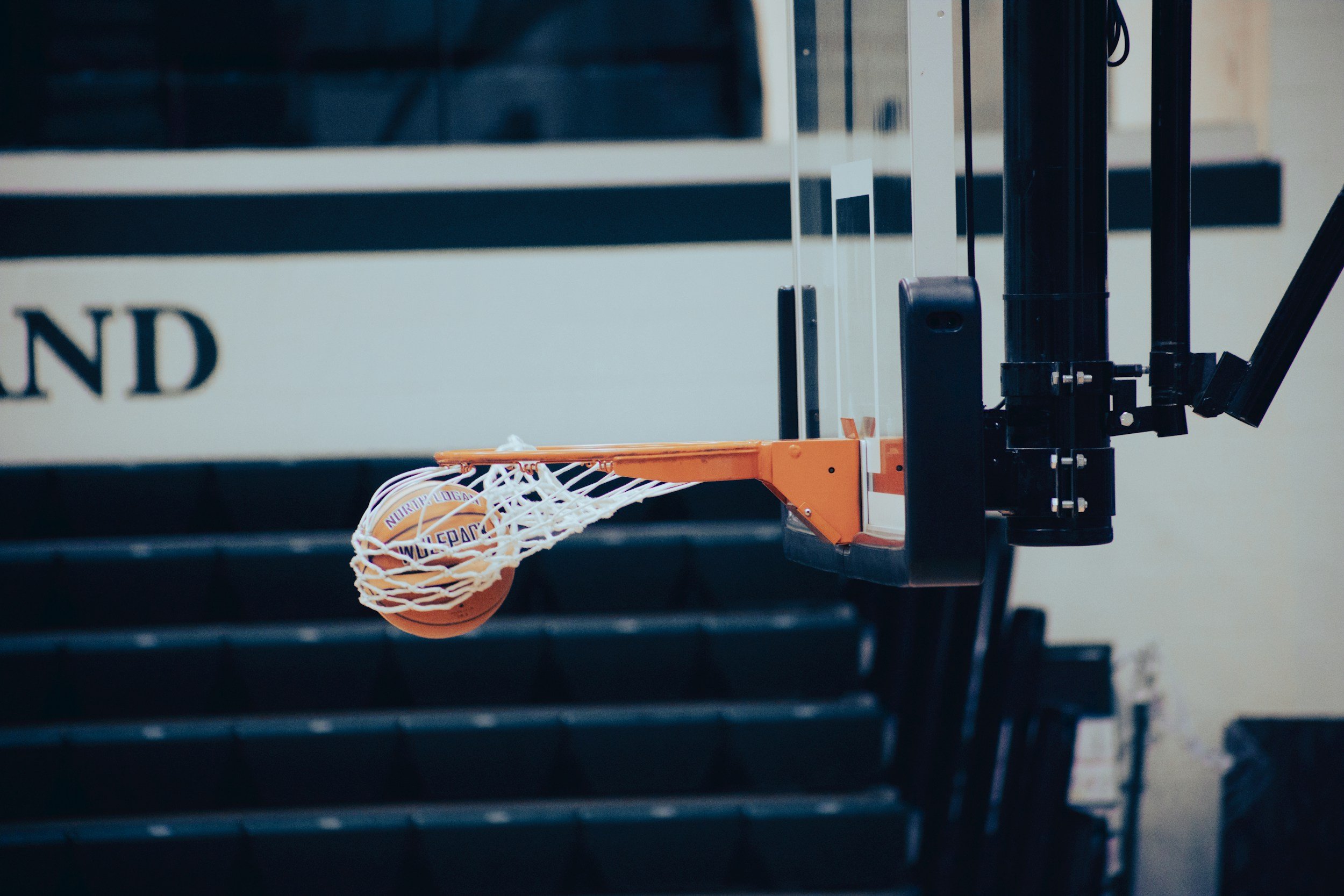 Basketball going through a basketball hoop in an indoor gym.
