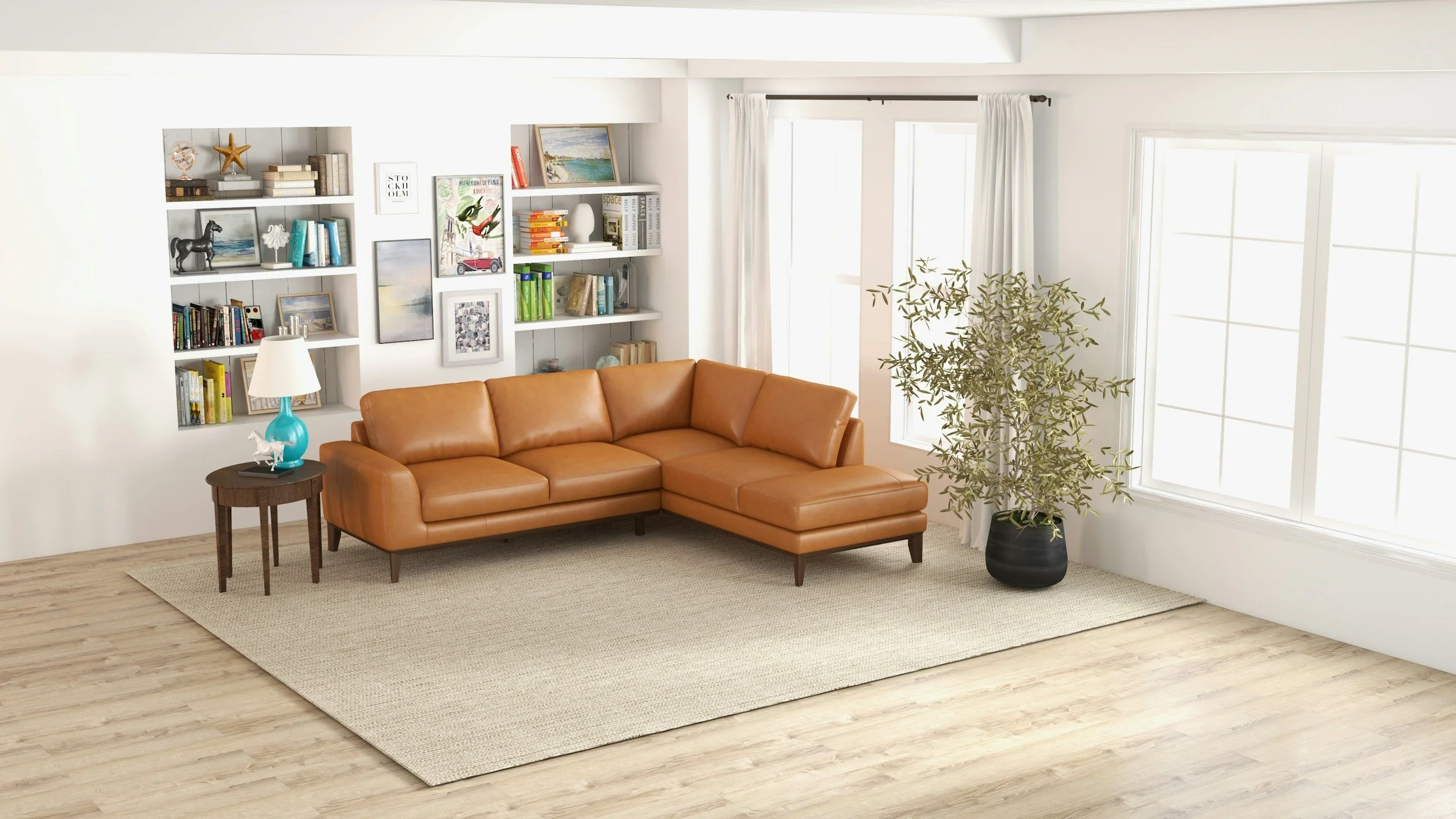 A cozy living room with a tan leather sectional sofa, a small wooden side table with a blue lamp that has a white shade, a large potted plant in a black pot, white walls with built-in shelves filled with books, artwork, and decorative items. Large windows with white curtains allow natural light into the space. The floor is light wood with a beige area rug.