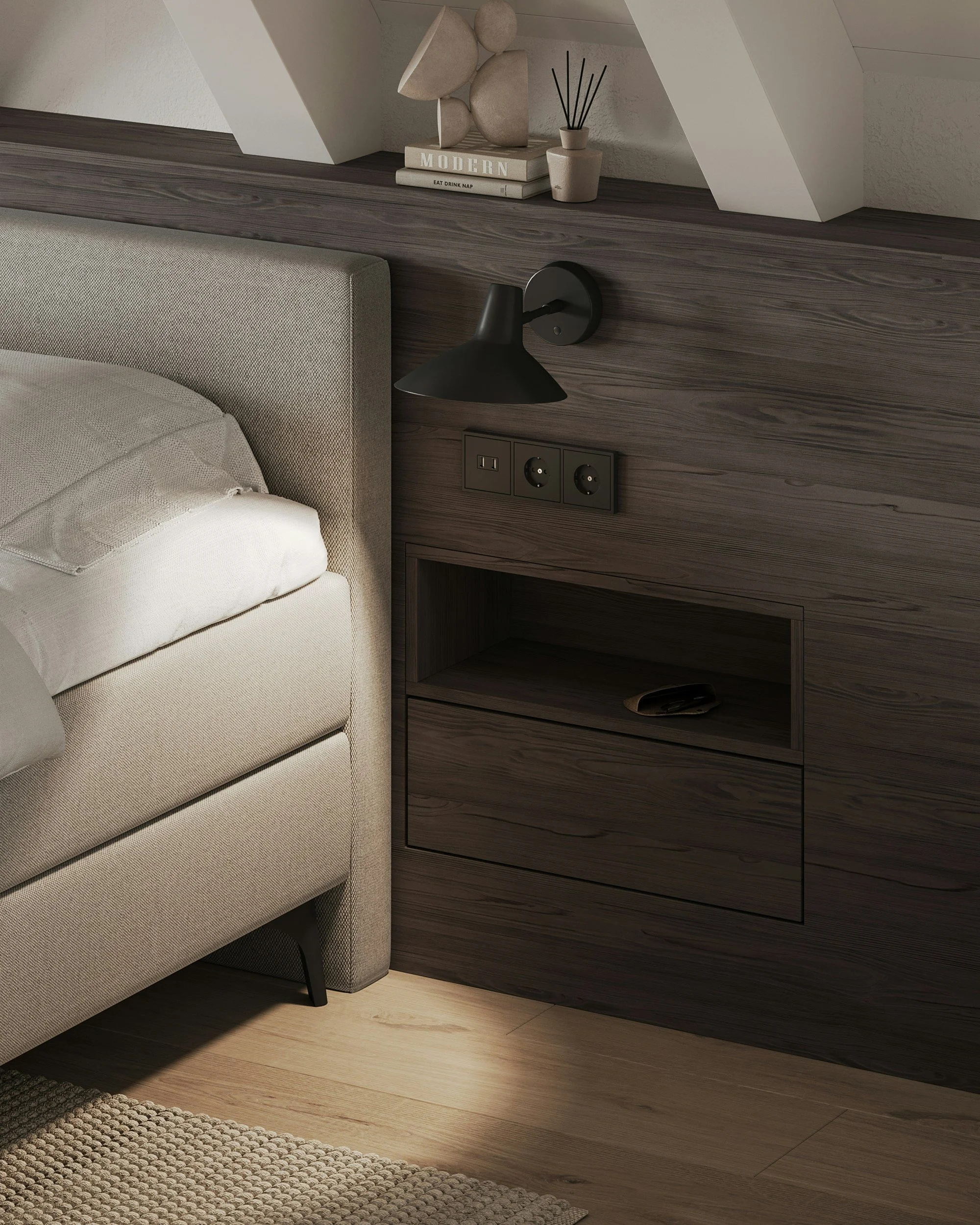 Close-up of a beige upholstered bed with a duvet and pillows, next to a dark wooden nightstand with a built-in shelf, wall-mounted black lamp, and electrical outlets, with decorative items on a shelf above.