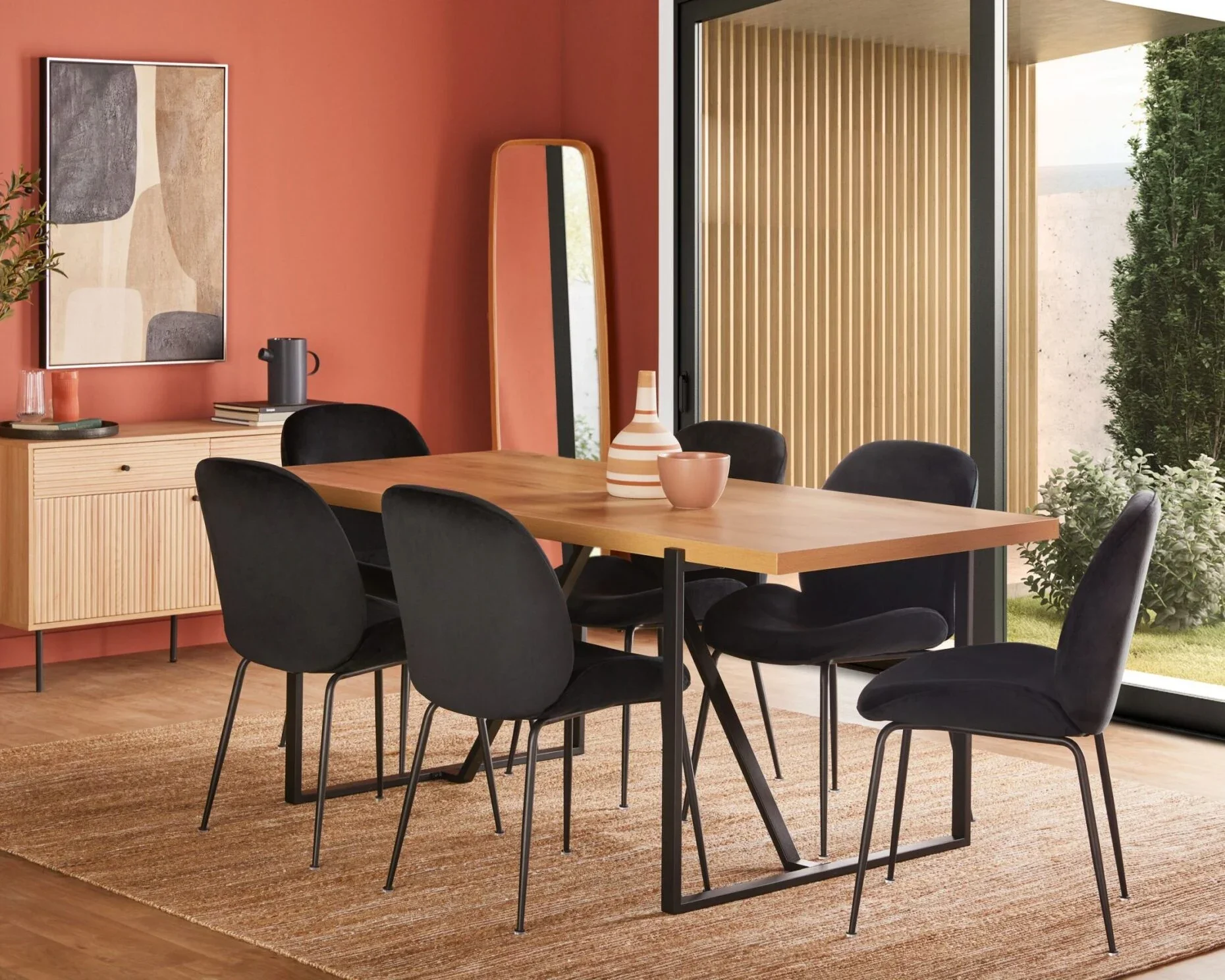 Wood dining table with black upholstered chairs, a sideboard and a red accent wall, shown as a room-layout reference