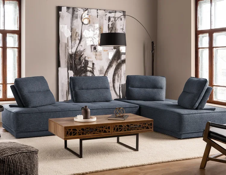 Modern living room with a dark blue sectional sofa, a wooden coffee table with decorative items, large abstract wall art, and floor lamps between two windows.