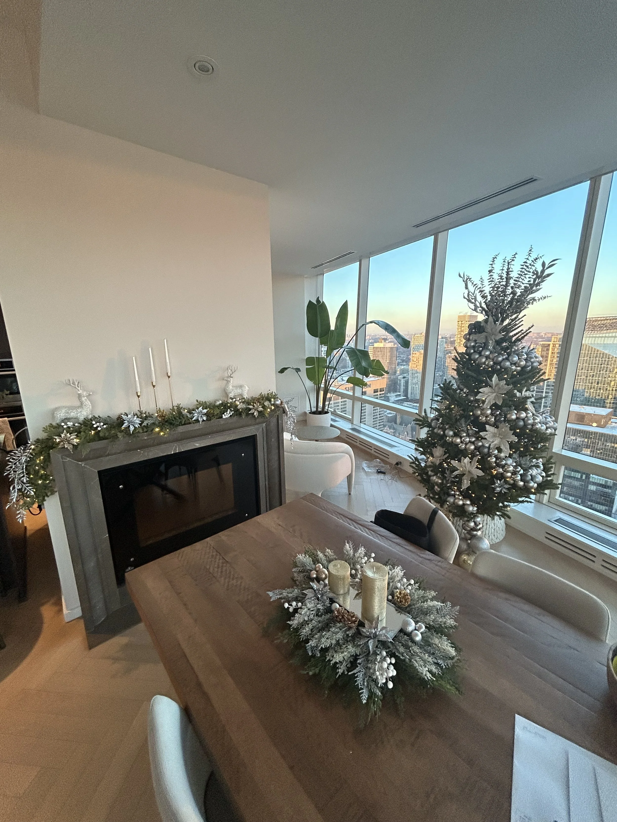 Living room decorated for Christmas with a small Christmas tree, candles, and garland on the fireplace