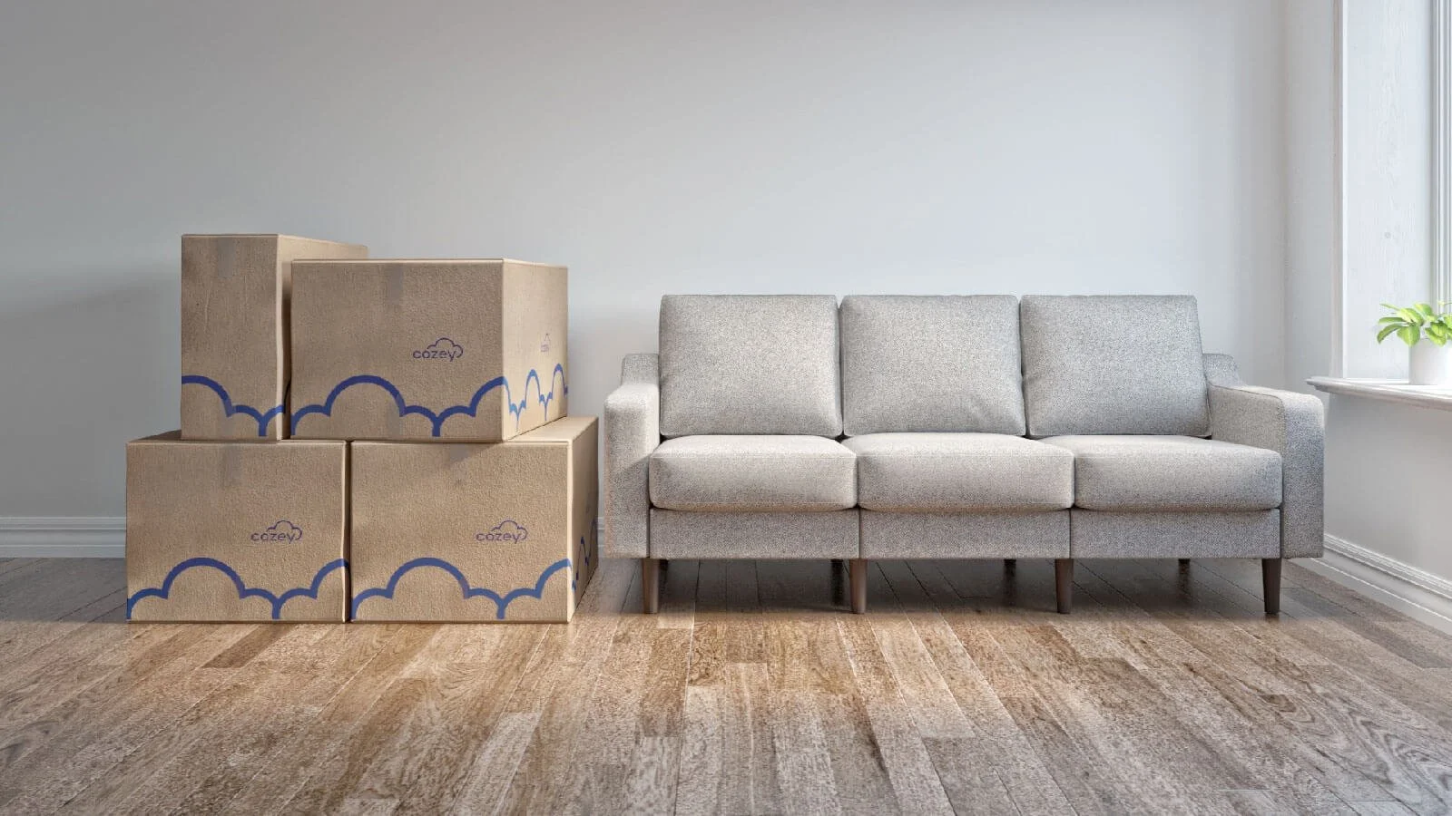 Stacked moving boxes next to a gray sofa in a room with wooden floors and a window with a plant on the sill.