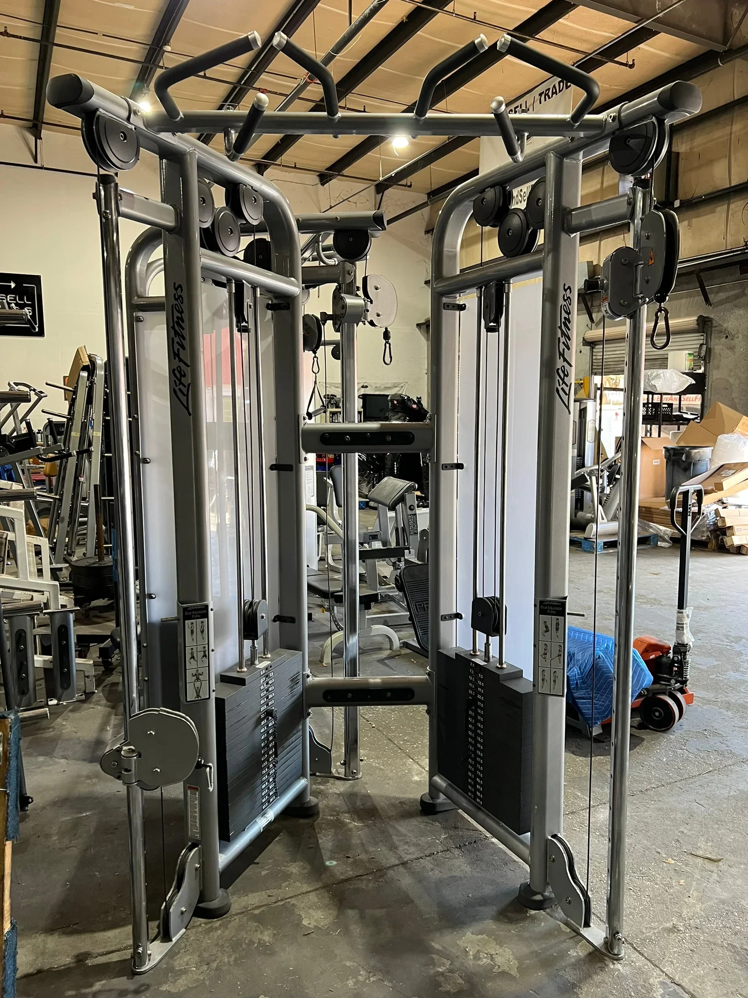 Heavy duty multi-exercise gym machine with weight stacks, pull-up bars, and handles in a warehouse setting.