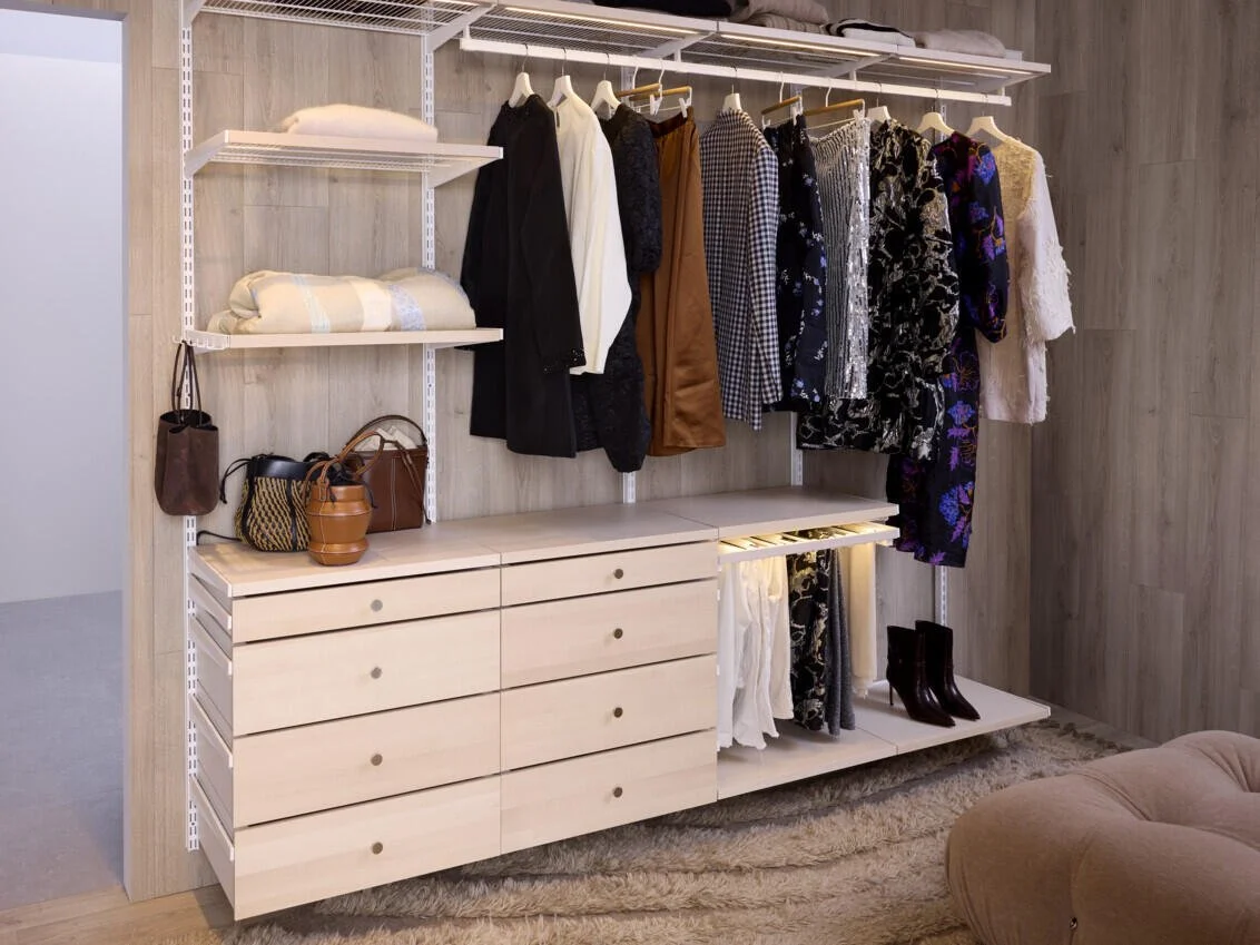 Open closet with hanging clothes and storage shelves.