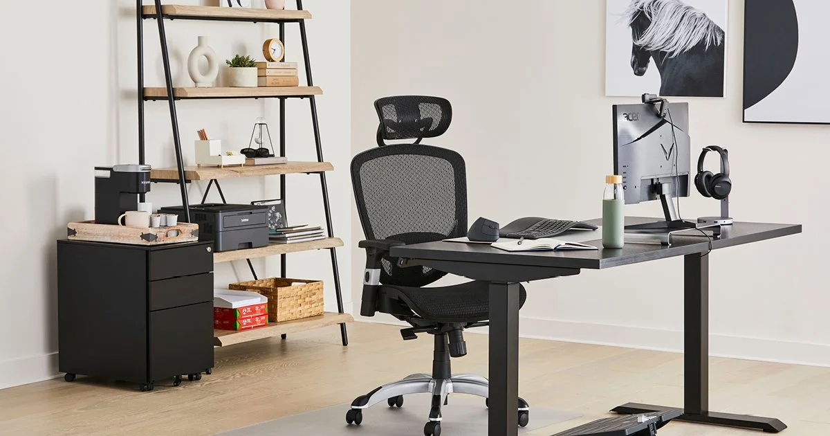 A modern home office with a black desk, ergonomic chair, computer monitor, and headphones, with a black shelving unit and artwork of a horse on the wall.