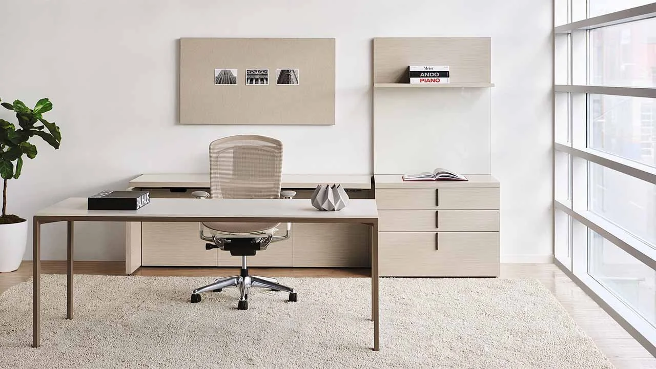 Modern office with a white desk, beige office chair, potted plant, wall art, and large windows with city view.