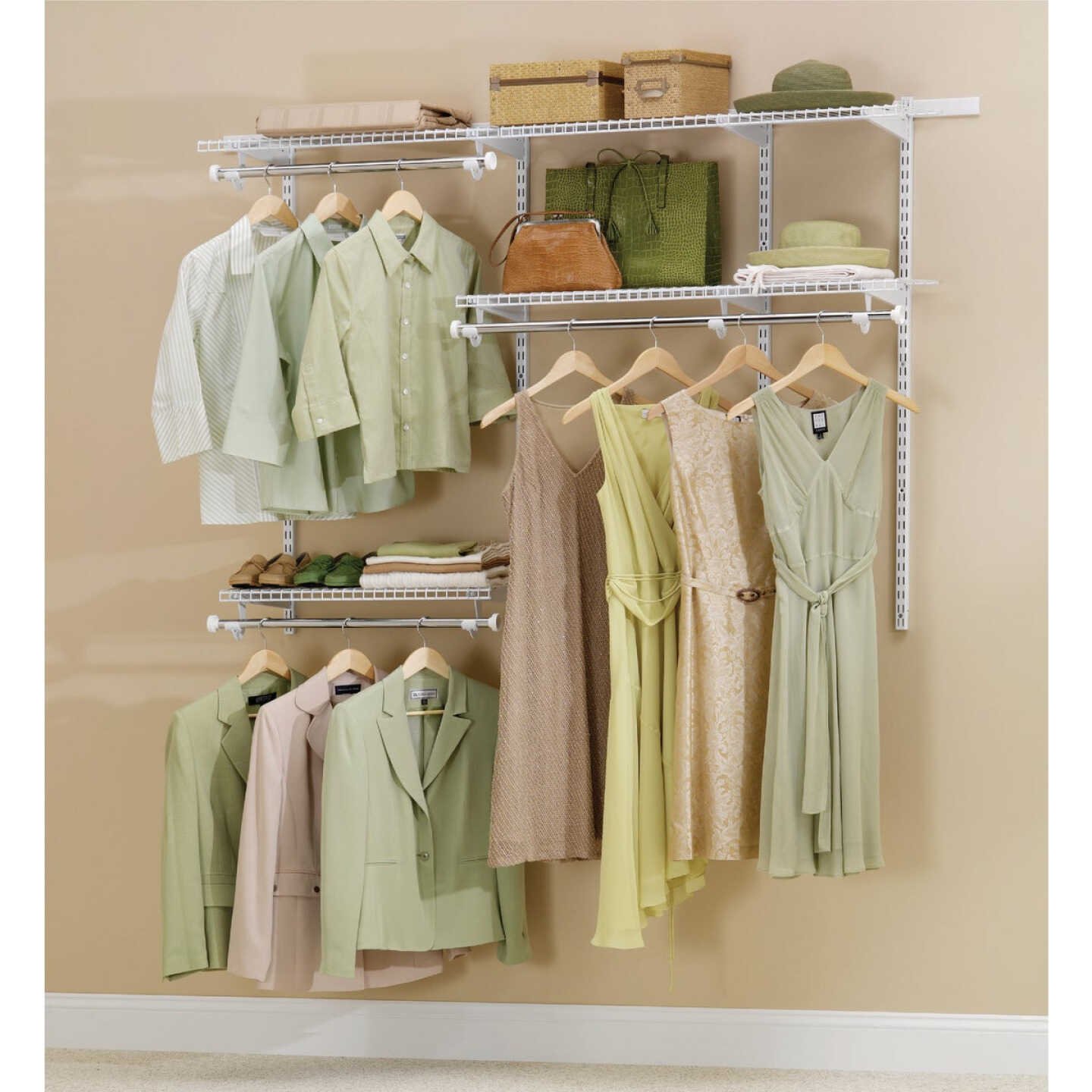 A closet wall with several light-colored shirts, jackets, and dresses hanging on wooden hangers, and folded clothes, bags, and storage boxes placed on white wire shelves.