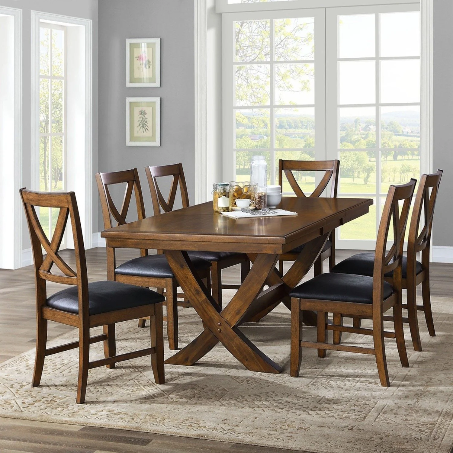 A dining room with six wooden chairs around a wooden table, set near large windows showing a green outdoor landscape.