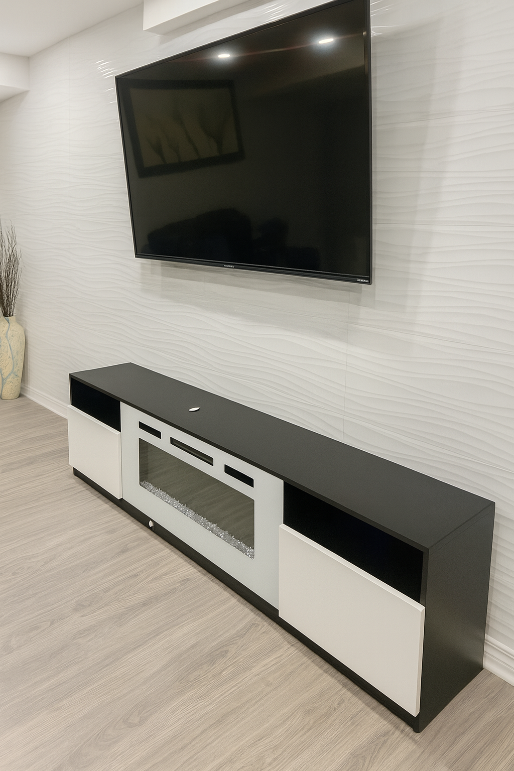 Modern black and white entertainment center with a flat-screen TV mounted on a textured white wall.