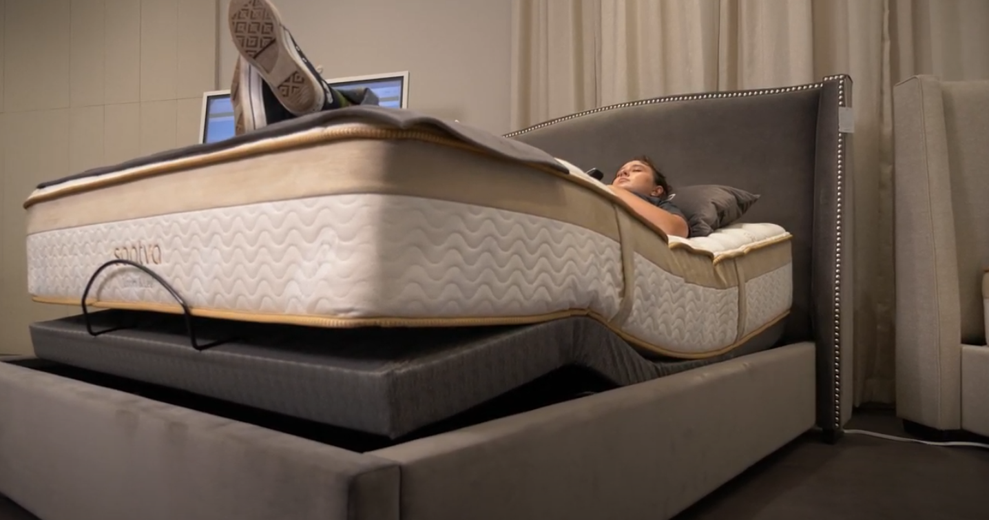 Person lying on a mattress on top of other mattresses in a bedroom.