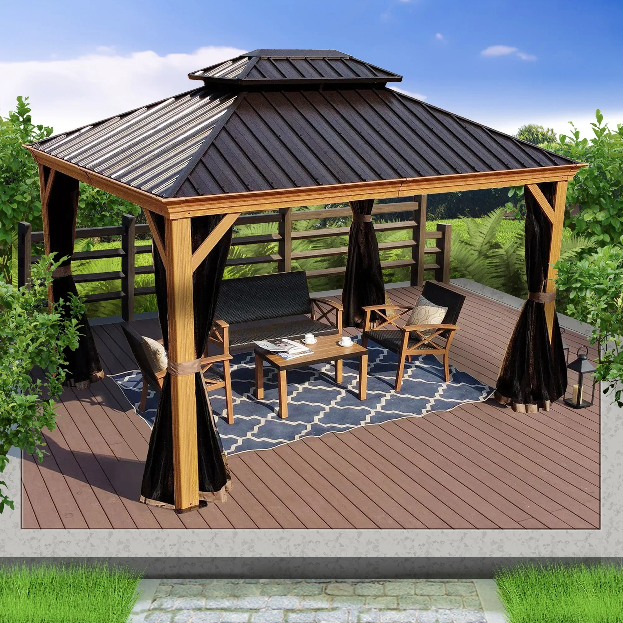Outdoor wooden gazebo with black curtains, outdoor furniture, and a blue patterned rug on a deck with trees and greenery in the background.