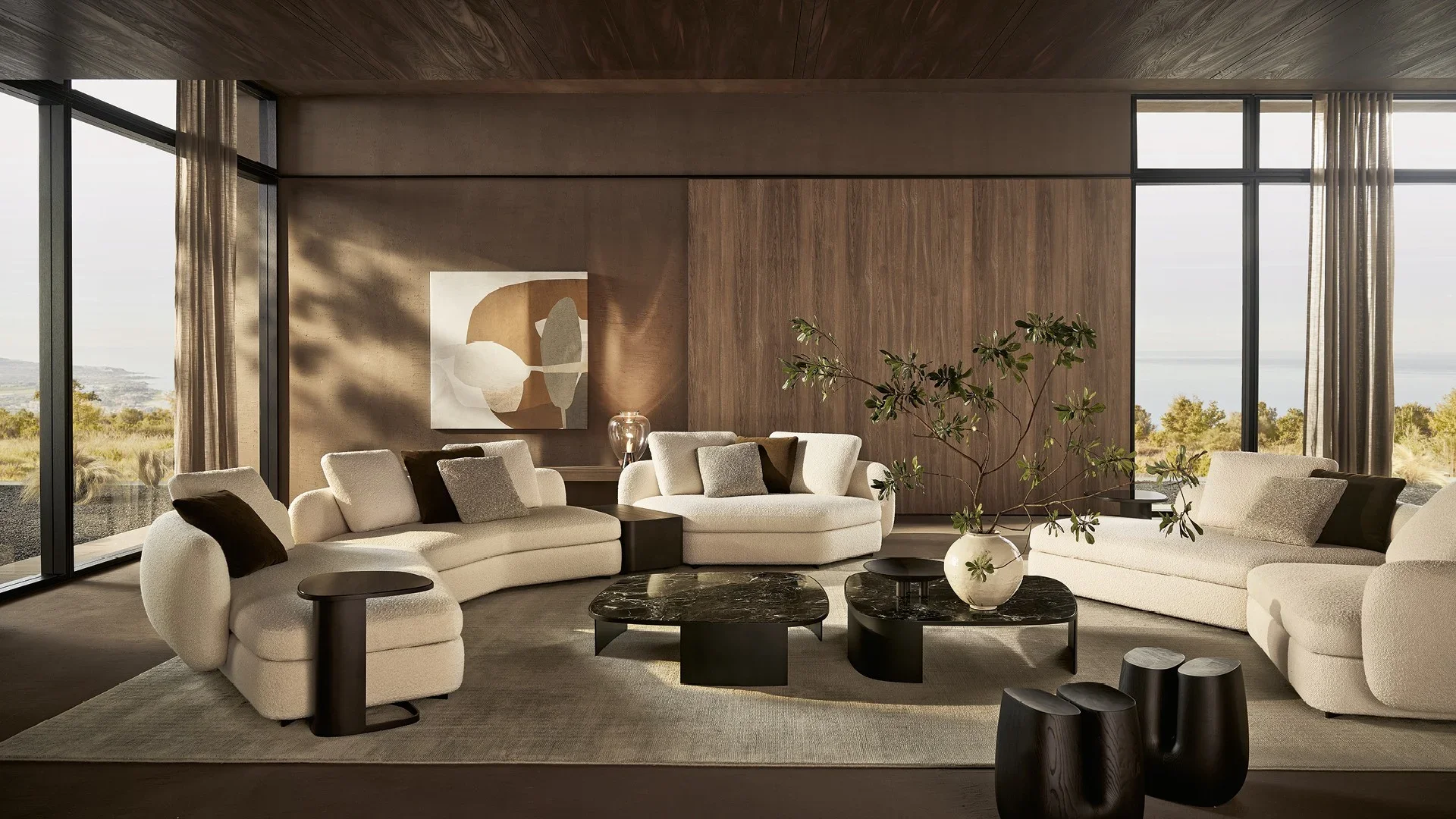Modern living room with large beige sectional sofas, black marble coffee tables, a large vase with green branches, abstract wall art, and floor-to-ceiling windows showing outdoor scenery.