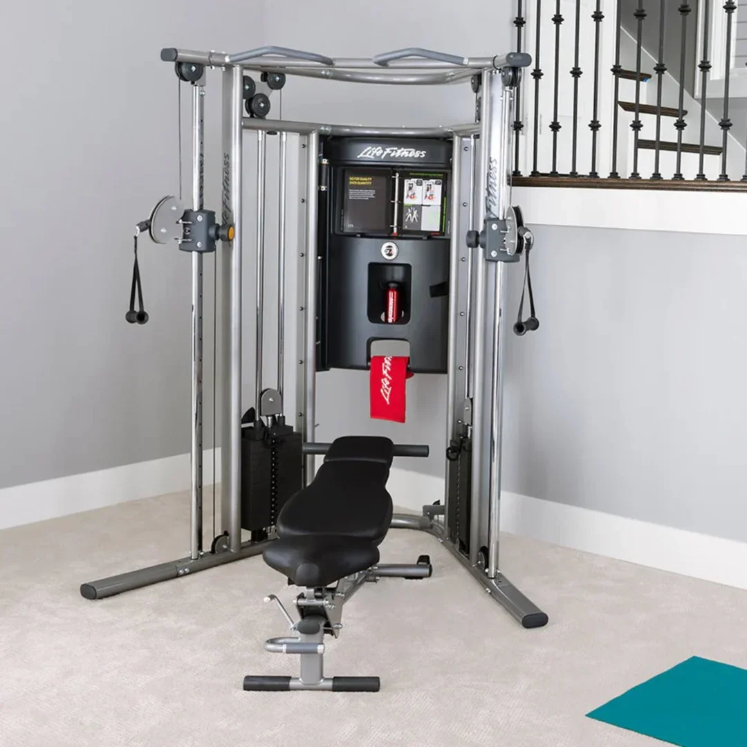 A home gym machine with a seat, pulleys, and a weight stack positioned against a gray wall.