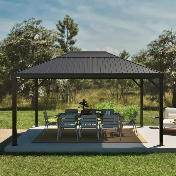Outdoor patio with a black metal gazebo covering a dining table and six chairs, with a potted plant and a rug underneath, on a grassy lawn with trees in the background.