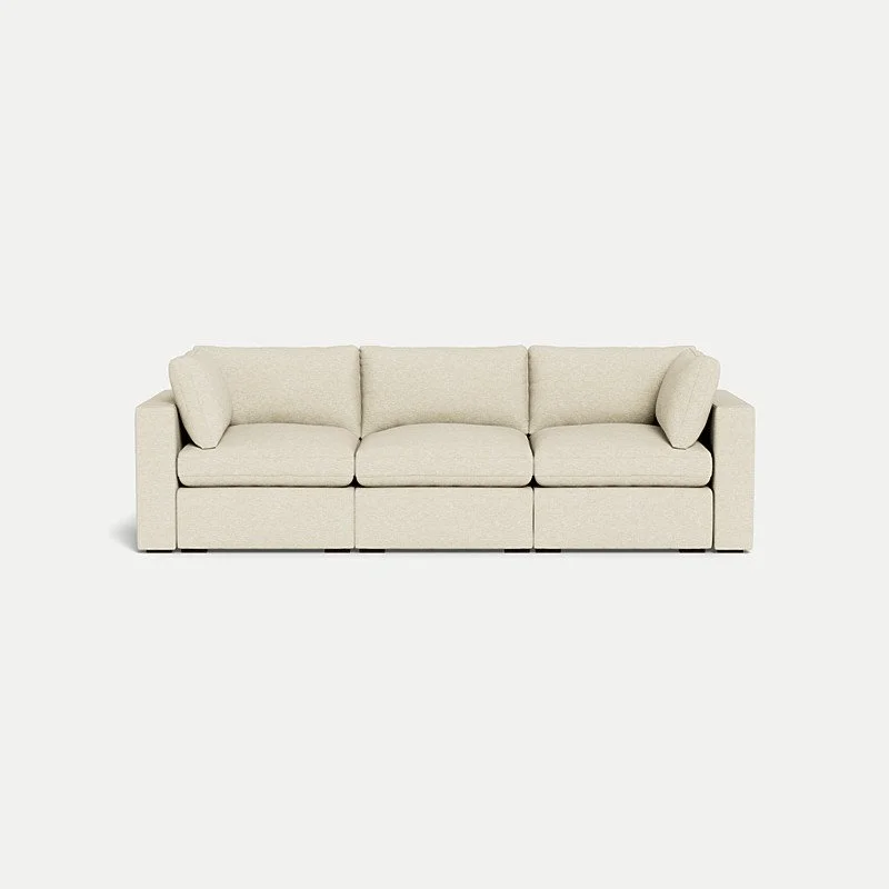 Cream-colored three-seater sofa with cushions against a plain white background.