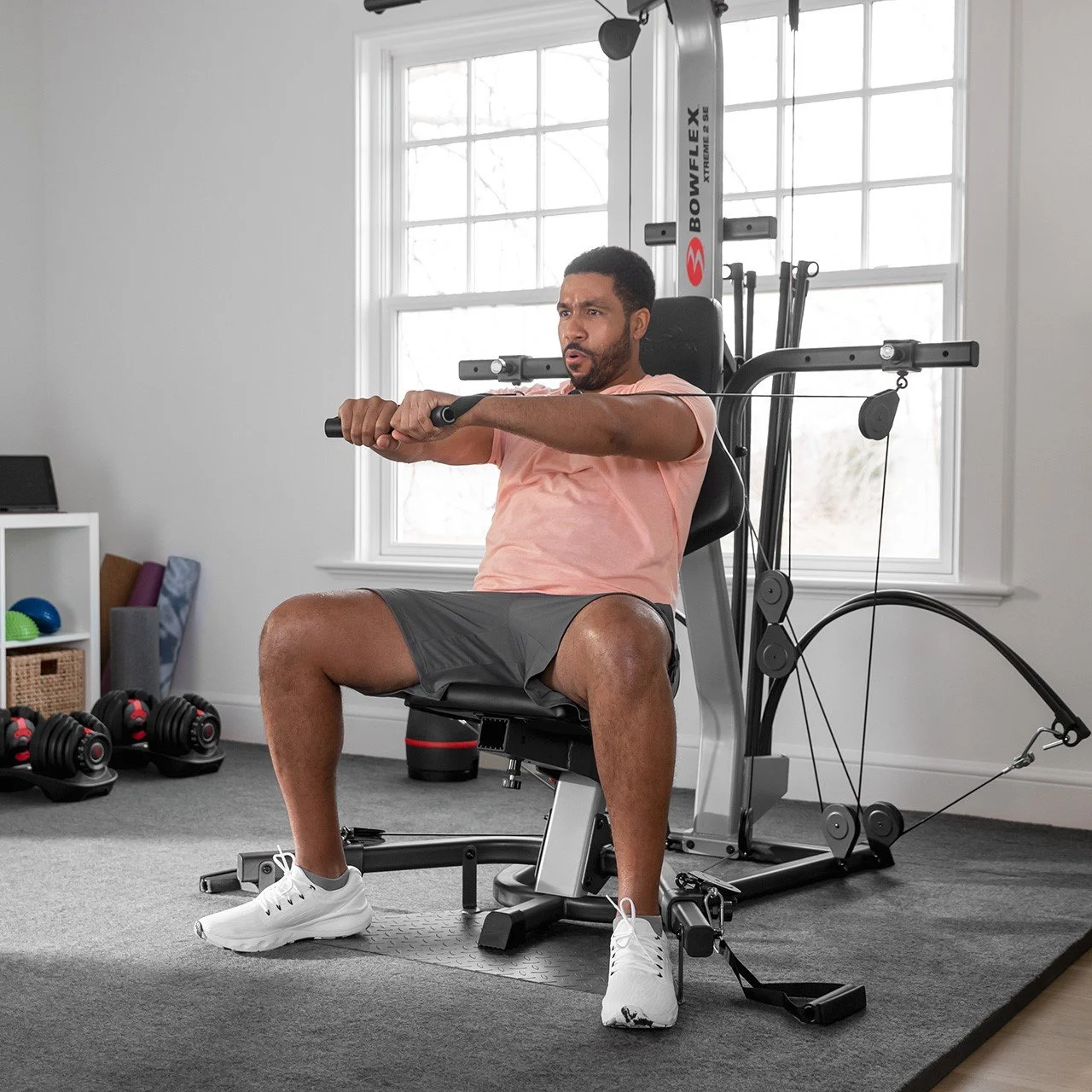 Man sitting on exercise machine using resistance bands for workout in home gym