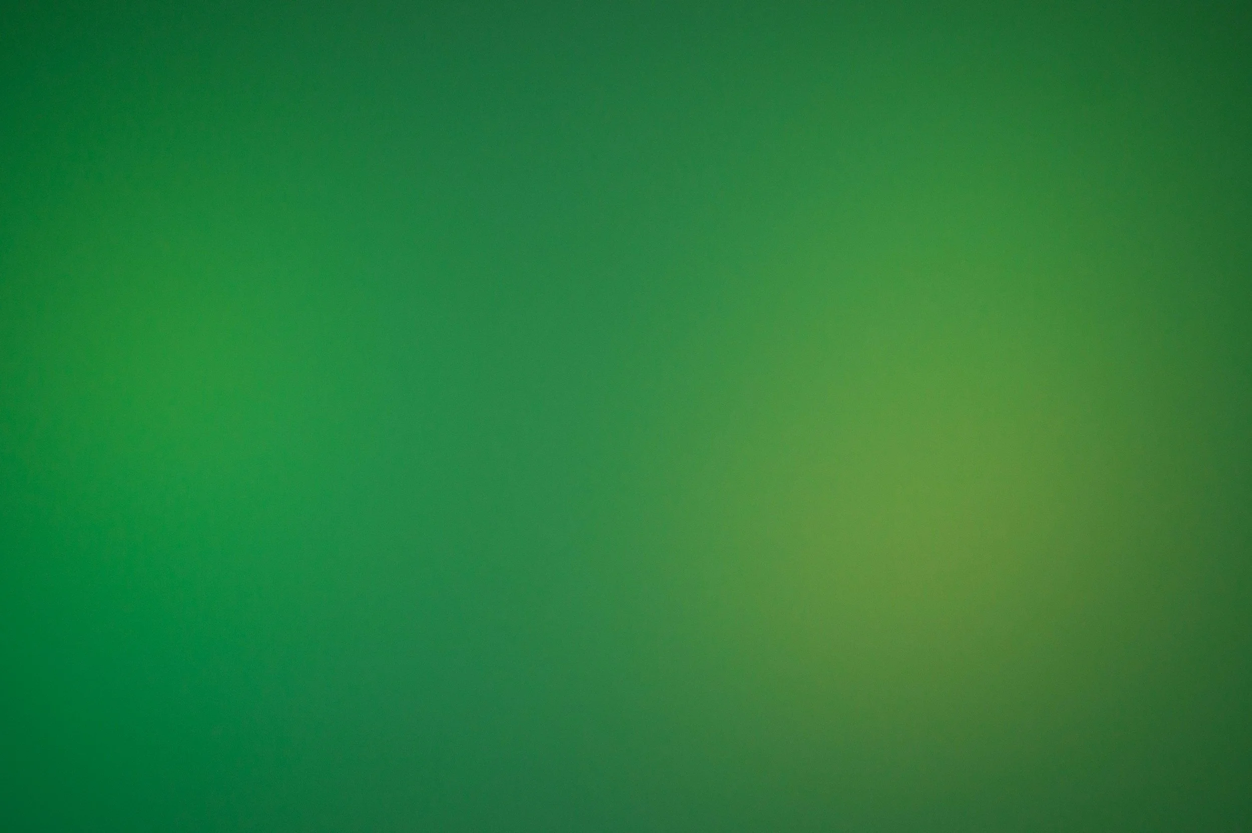 Blurred green abstract background with smooth gradient transitions.