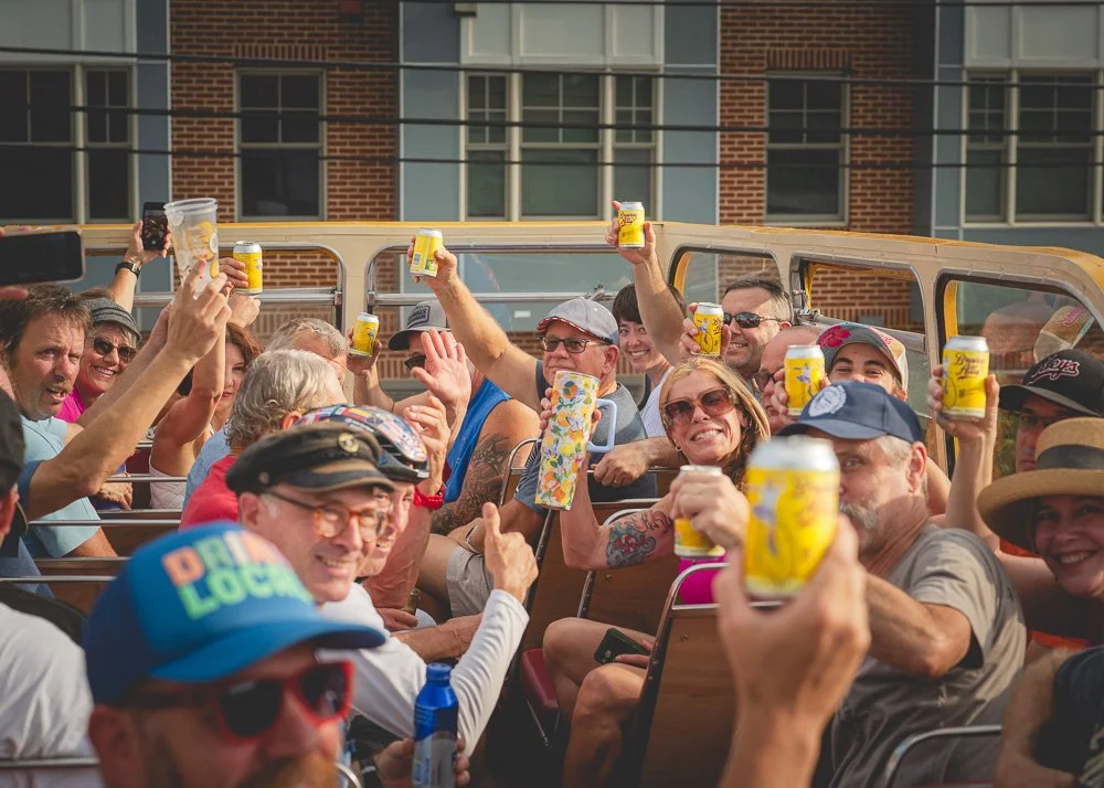 Group of people enjoying a boat ride, holding yellow drinks and smiling.