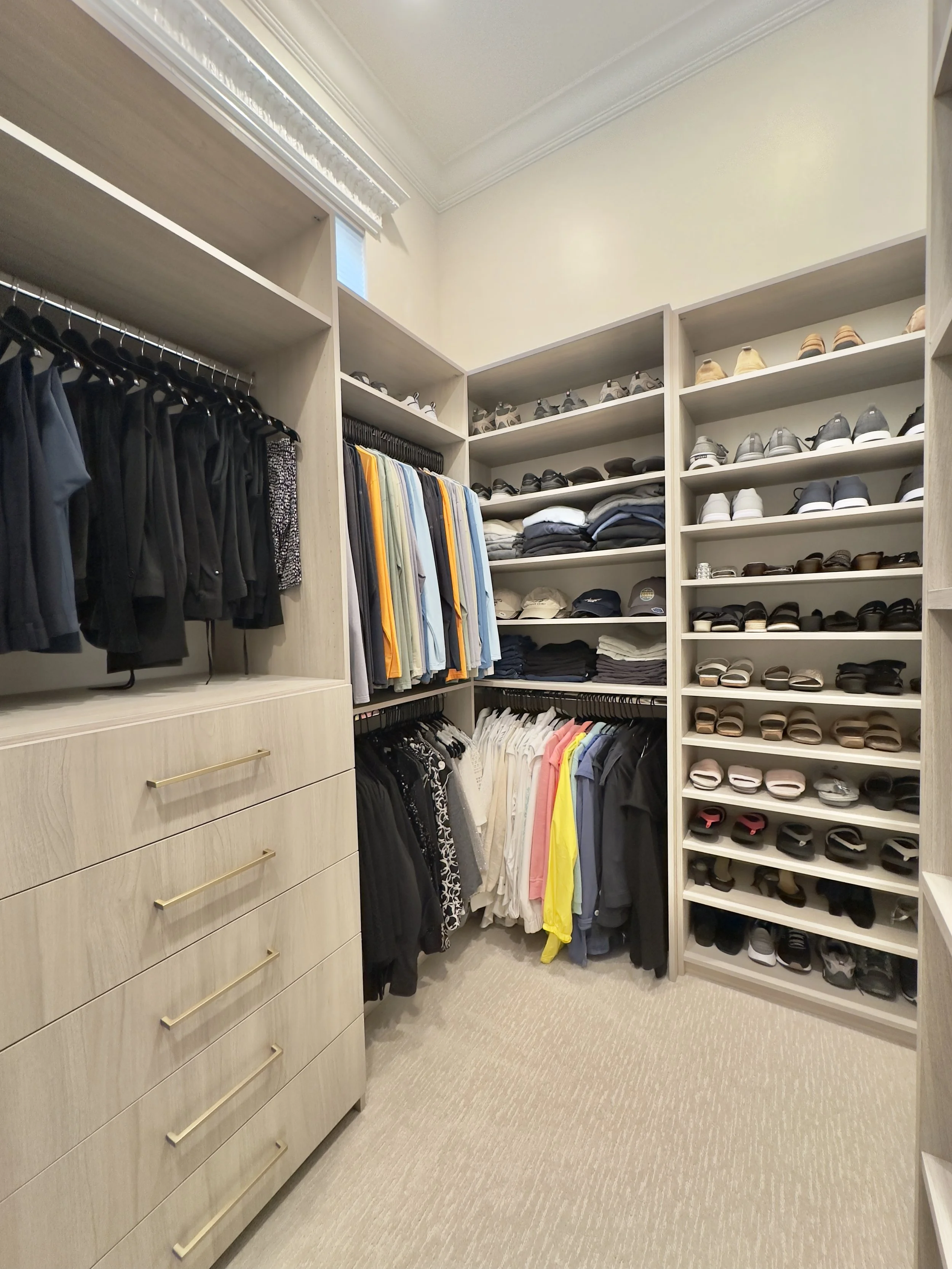 A walk-in closet with organized clothing, shoes, and accessories on shelves and hanging rods.