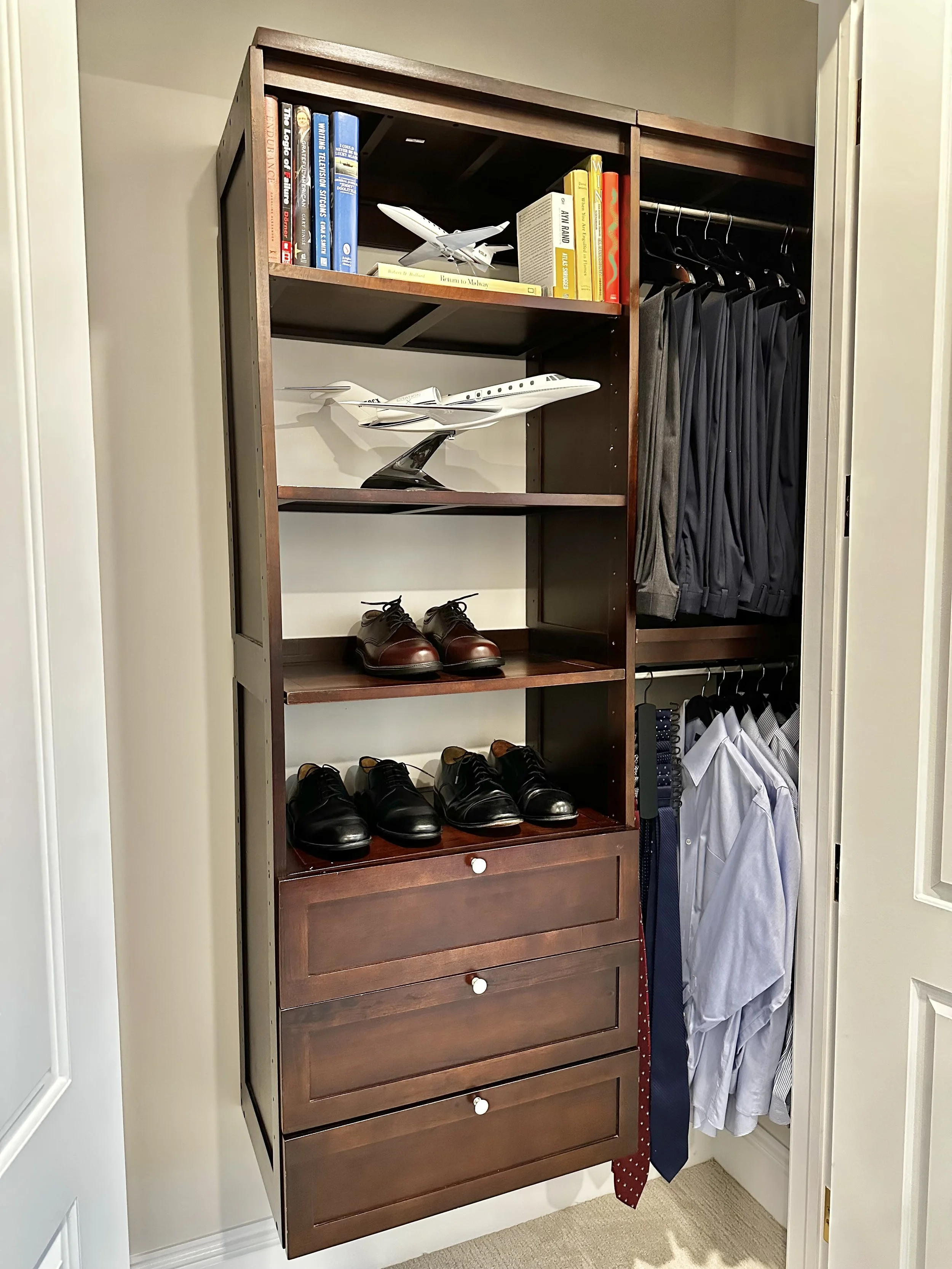 Closet with dress shoes, dress shirts, ties, books, and model airplanes.