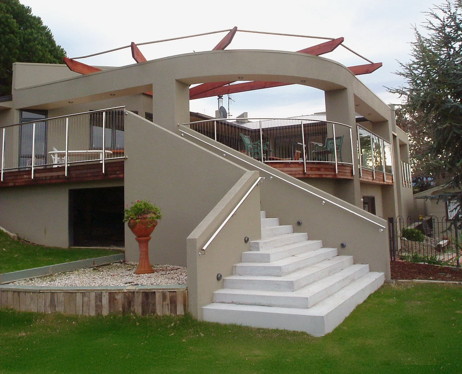 Modern two-story house with a rooftop deck, outdoor stairs, and a landscaped yard.