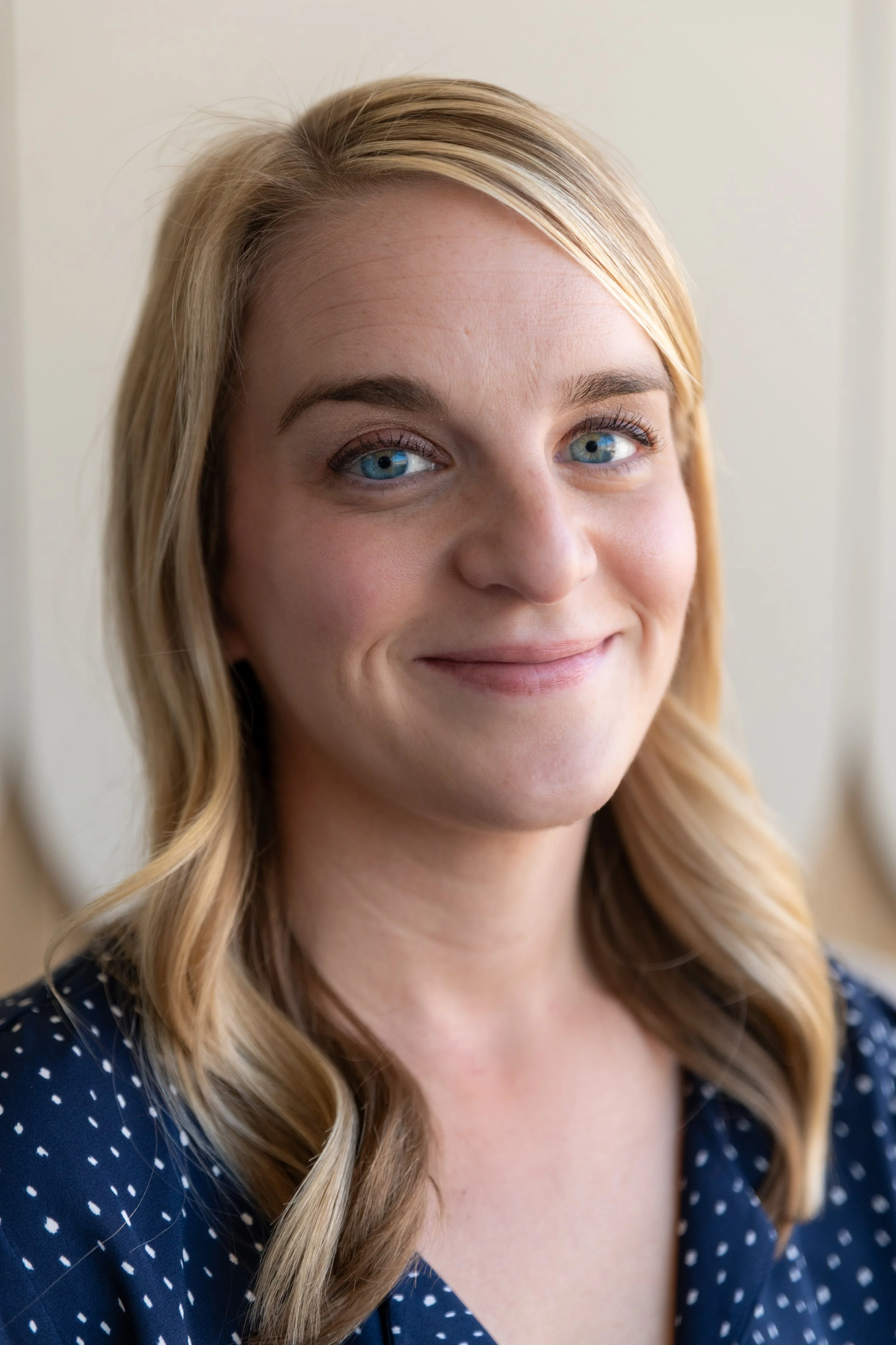 Close-up of a smiling woman with blonde hair and blue eyes.