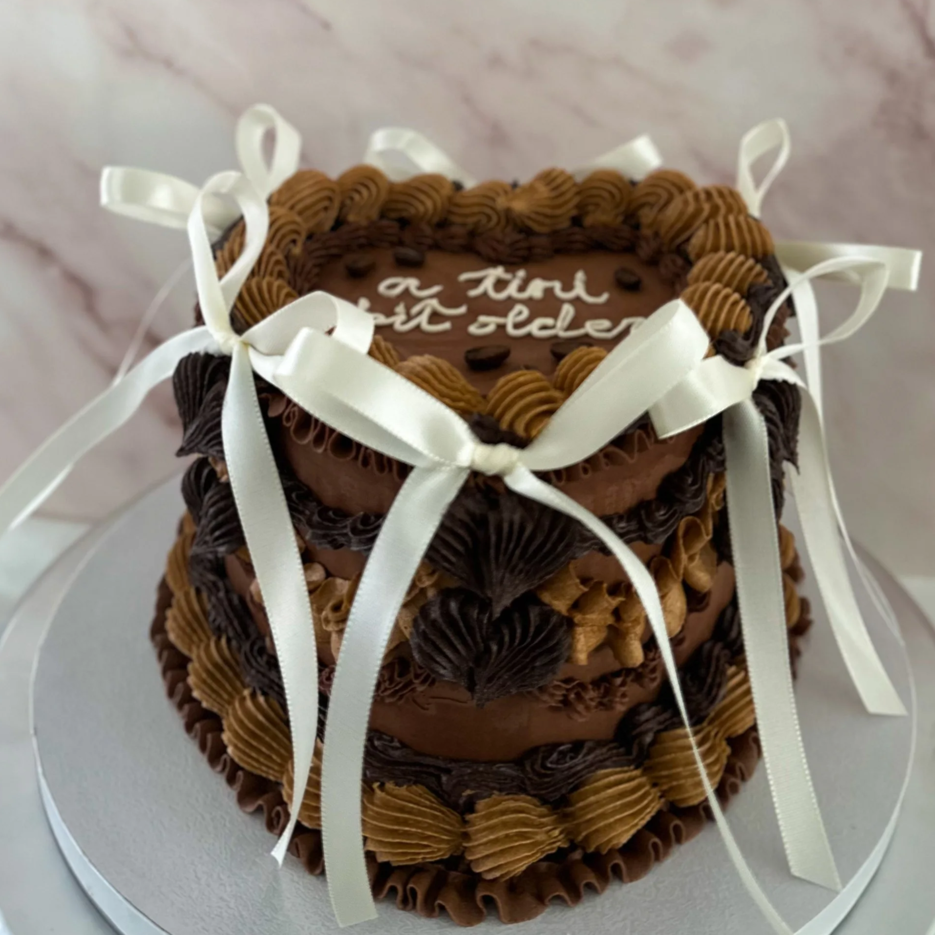 Close-up of a white frosted cake decorated with small yellow and blue flowers and green leaves.