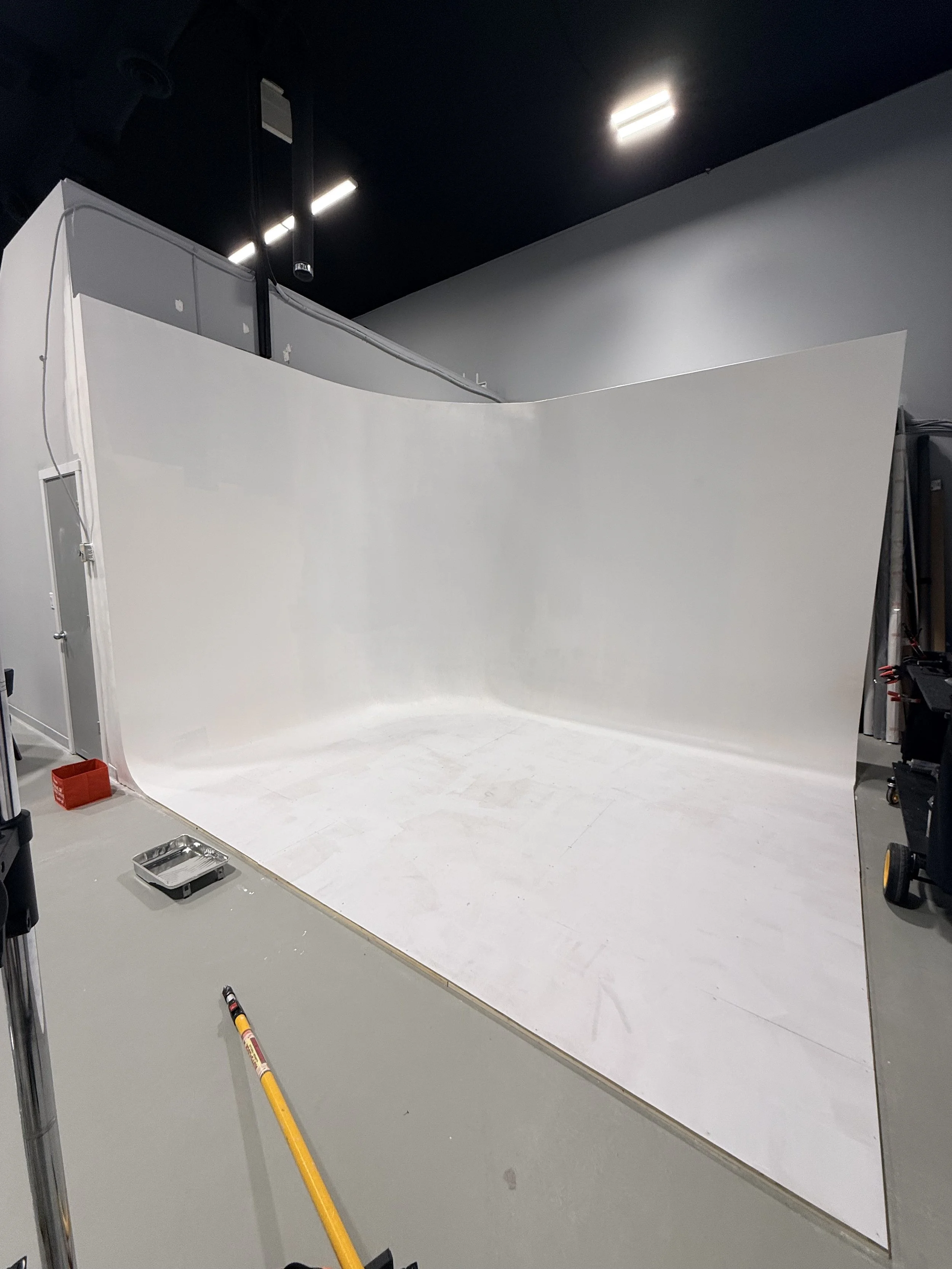 Photography studio with white cyclorama wall and ceiling mounted lighting fixtures.