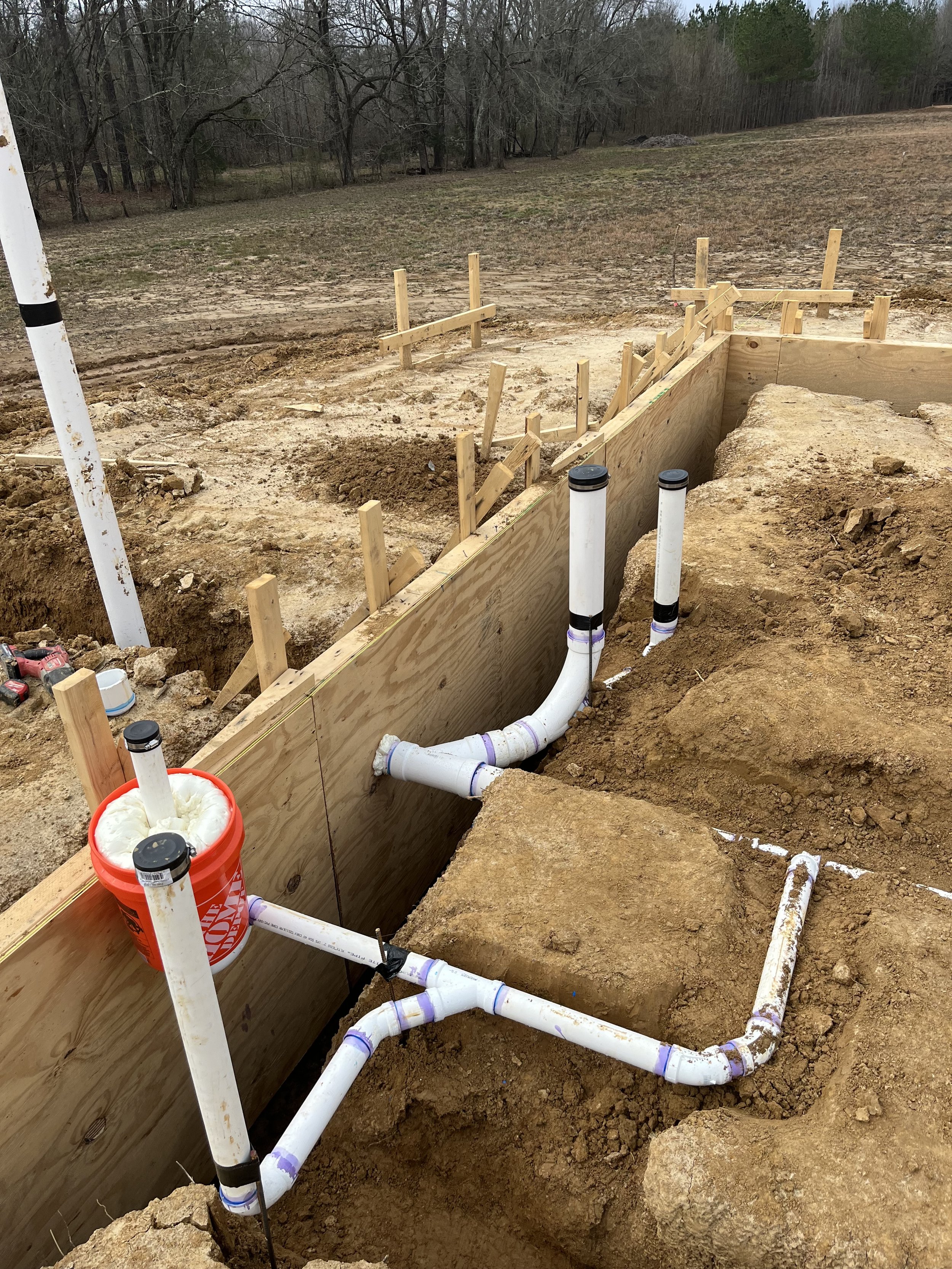 Scenic landscape with a large body of water in the foreground, surrounded by grassy hills and mountains under a cloudy sky.
