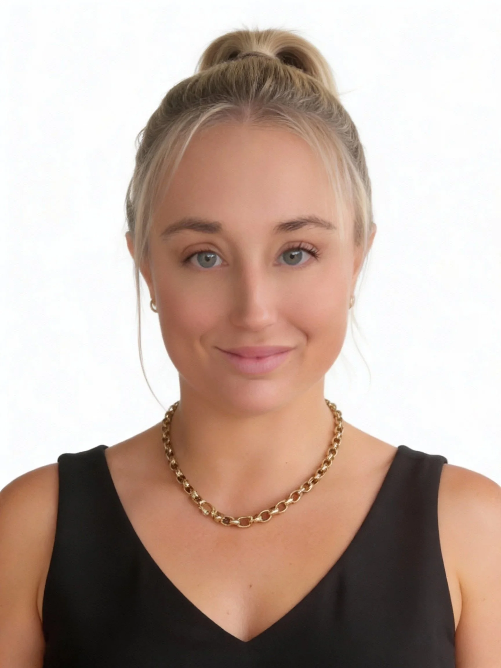 Young woman with blonde hair tied in a high ponytail, wearing a black sleeveless top and a gold chain necklace, smiling softly against a plain white background.