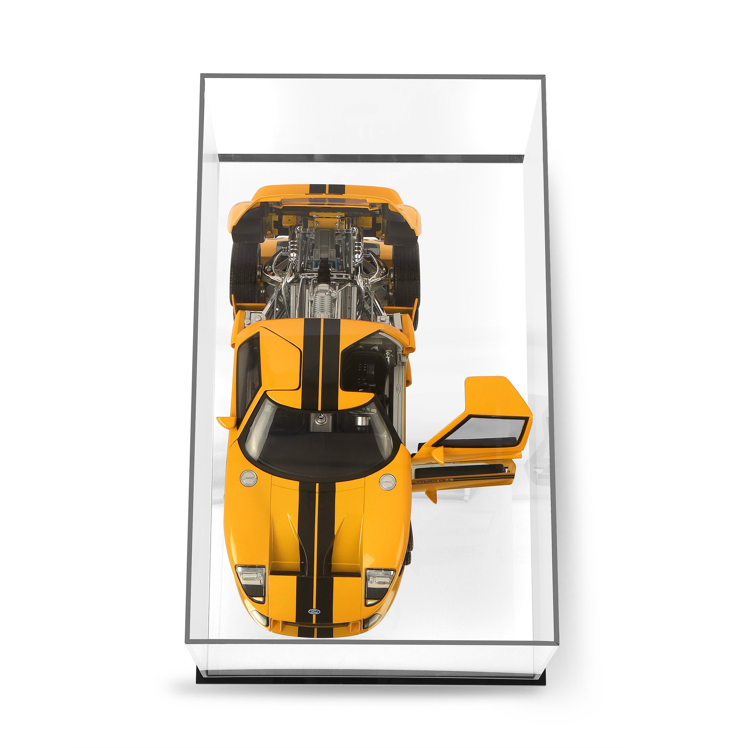 Top view of a yellow sports car with black racing stripes inside a glass display case.
