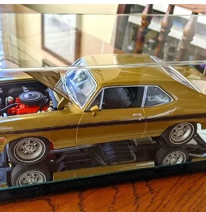 A model gold-colored classic car displayed on a glass shelf.