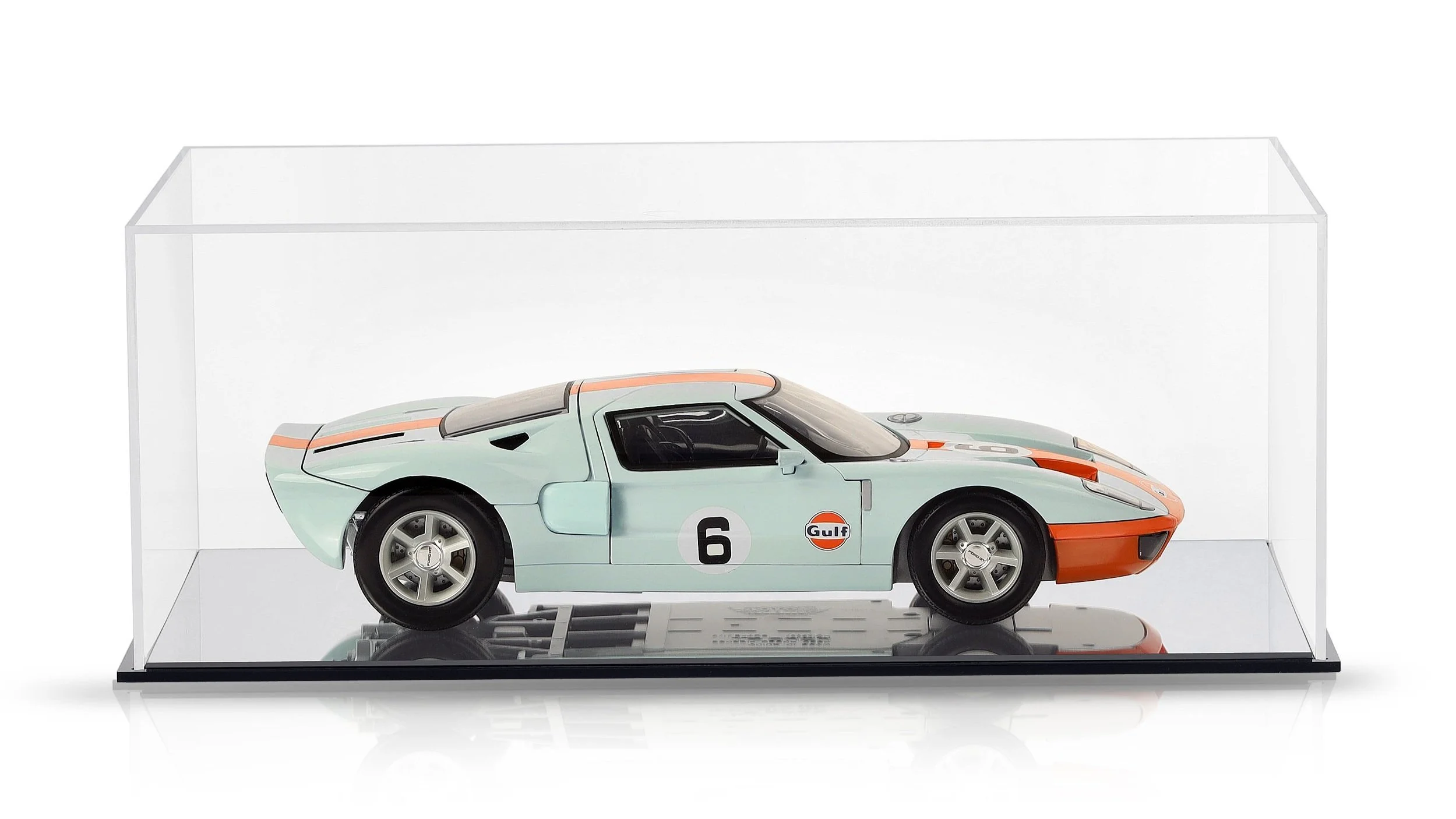 Model of a vintage race car inside a clear display case, with Gulf logo and racing number 6, light blue with orange accents.