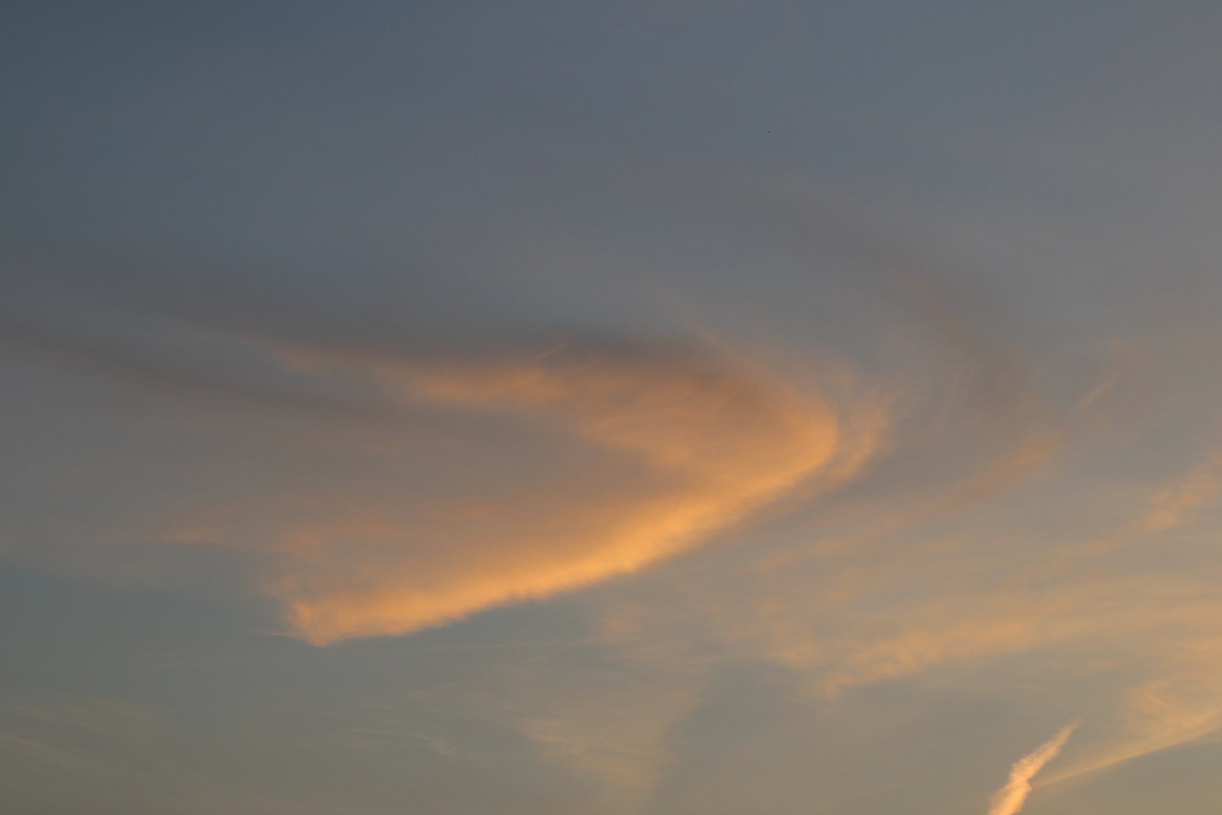 Clouds in the sky illuminated by the setting or rising sun, with shades of orange and gray.