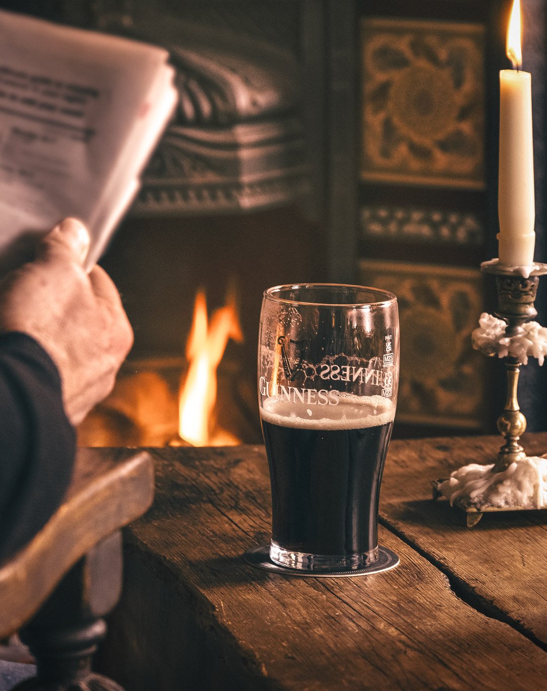 A customer enjoys a Pint of Guinness, whilst reading his paperby the fire at The Ship pub in Upavon, Wiltshire