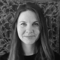 Black-and-white portrait of a woman with long hair, smiling slightly, with patterned background.